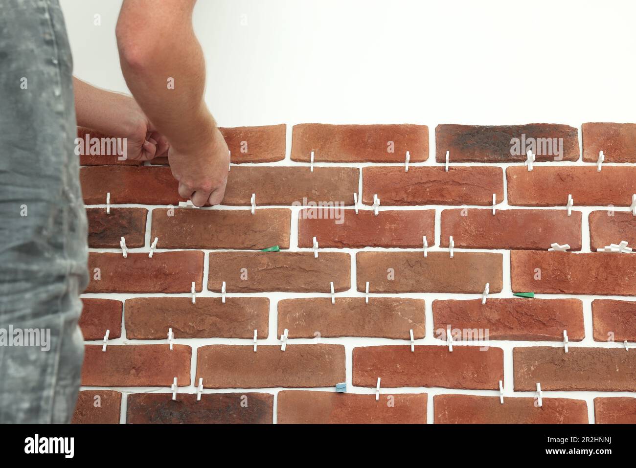 Professional builder gluing decorative brick on wall, closeup. Tiles installation process Stock Photo