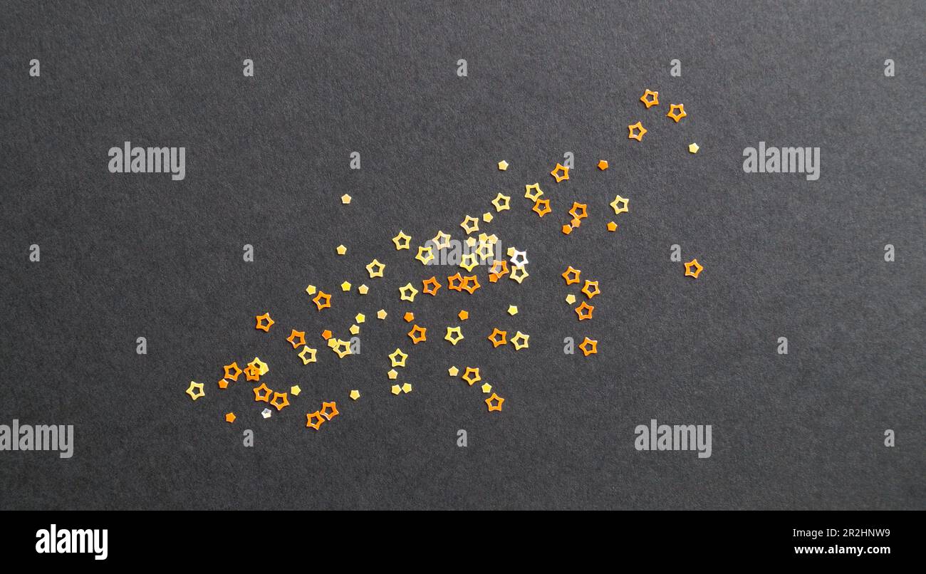 Many beautiful star shaped sequins on black background, flat lay Stock Photo