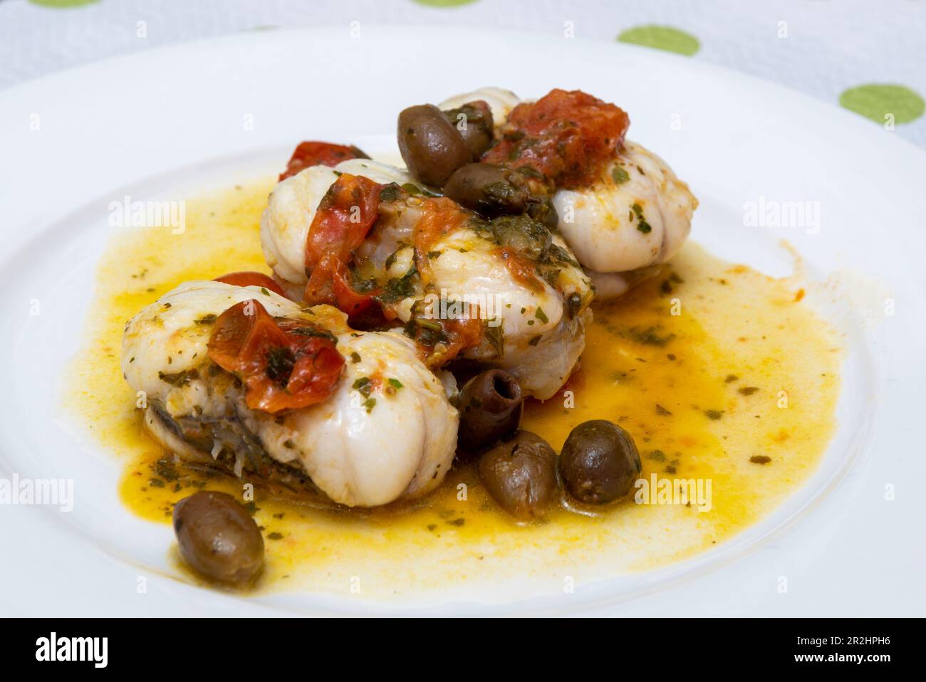 Fresh monkfish with cherry tomatoes and olives. Stock Photo