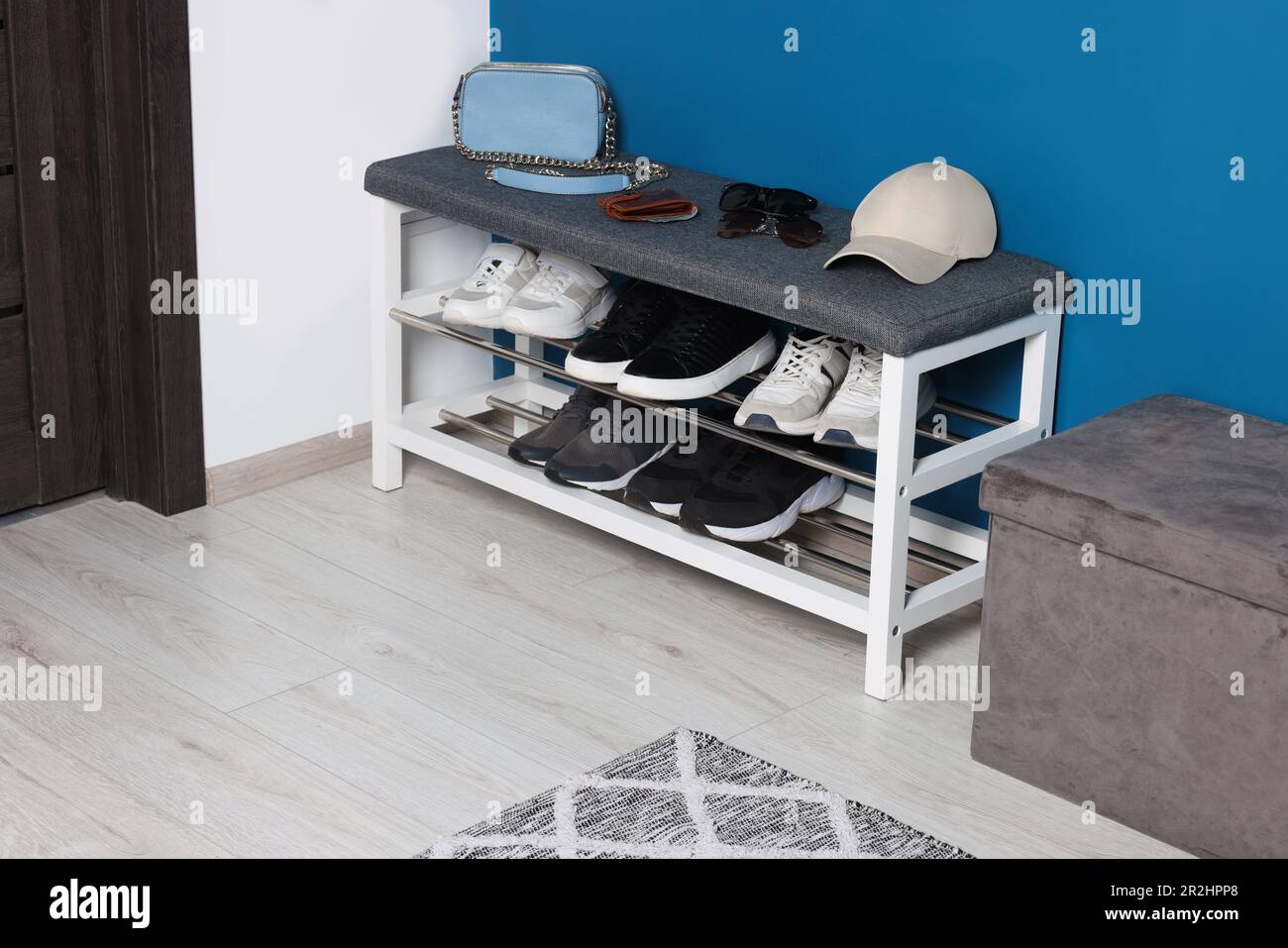 Stylish hallway with shoe storage bench and ottoman near blue wall. Interior design Stock Photo