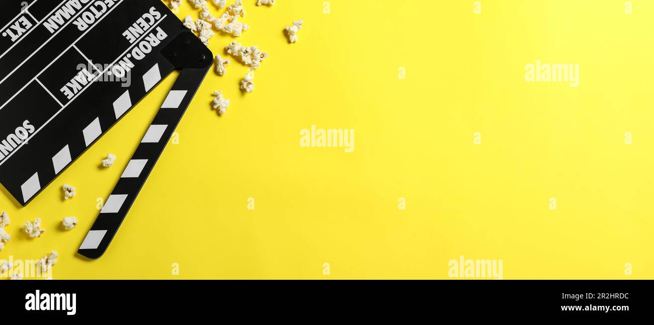 Clapper Banner Clapper board and popcorn on yellow background, flat lay with space for ...