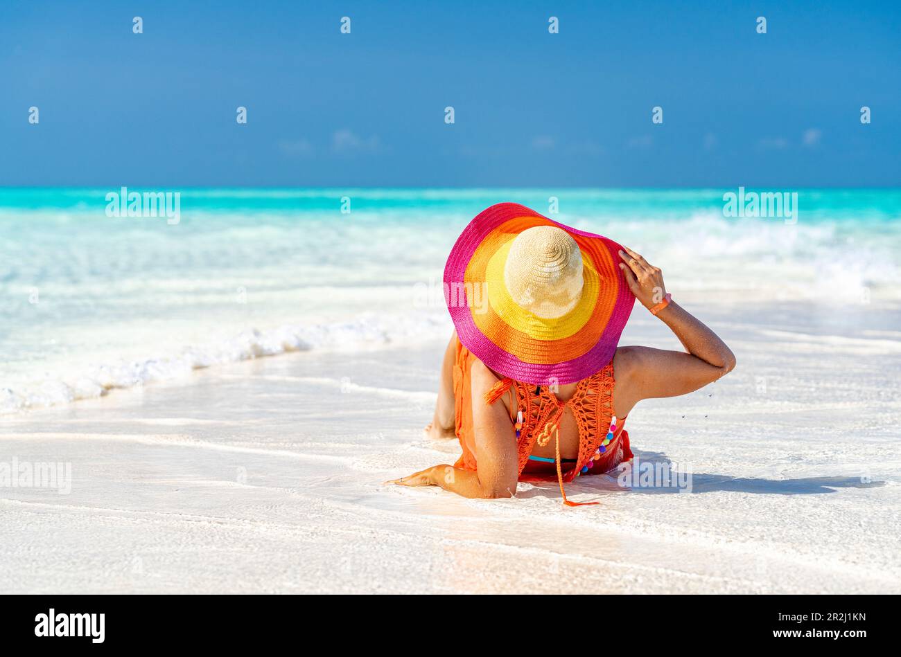 Woman with hat relaxing on idyllic empty beach, Zanzibar, Tanzania, East Africa, Africa Stock Photo