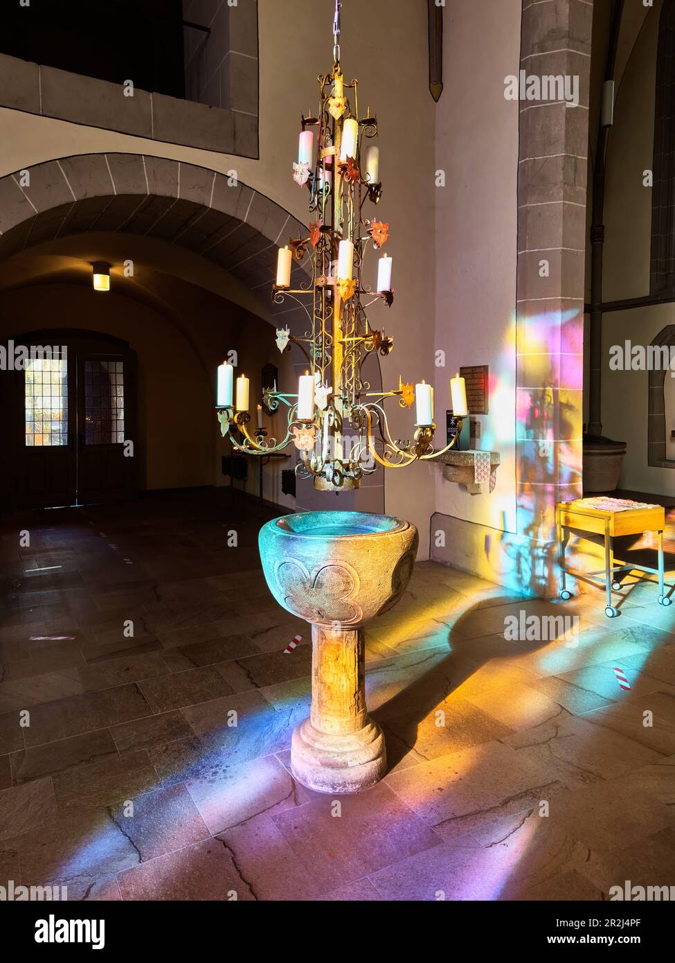 Holy water font with historic candlestick in the sun shining through a