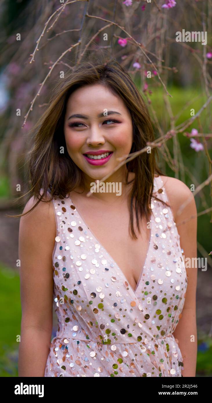 Beautiful Young Woman in Pink Gown Standing Under Blooming Weeping Higan Cherry Tree | Garden | Late Afternoon Stock Photo