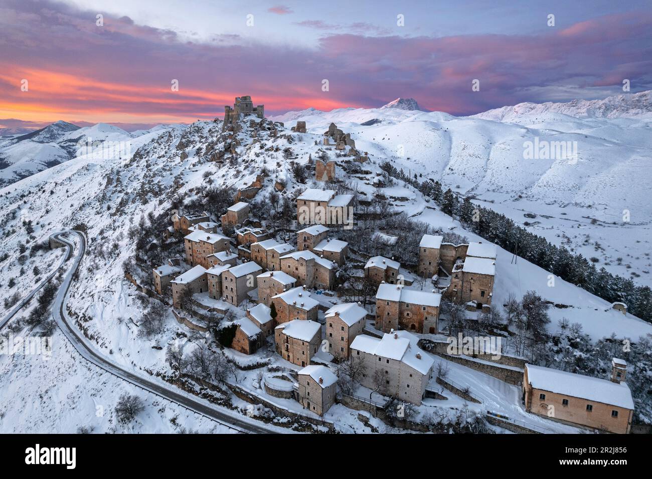 Aerial winter view of the snow covered medieval village of Rocca Calascio with the castle and pink clouds at dusk Stock Photo