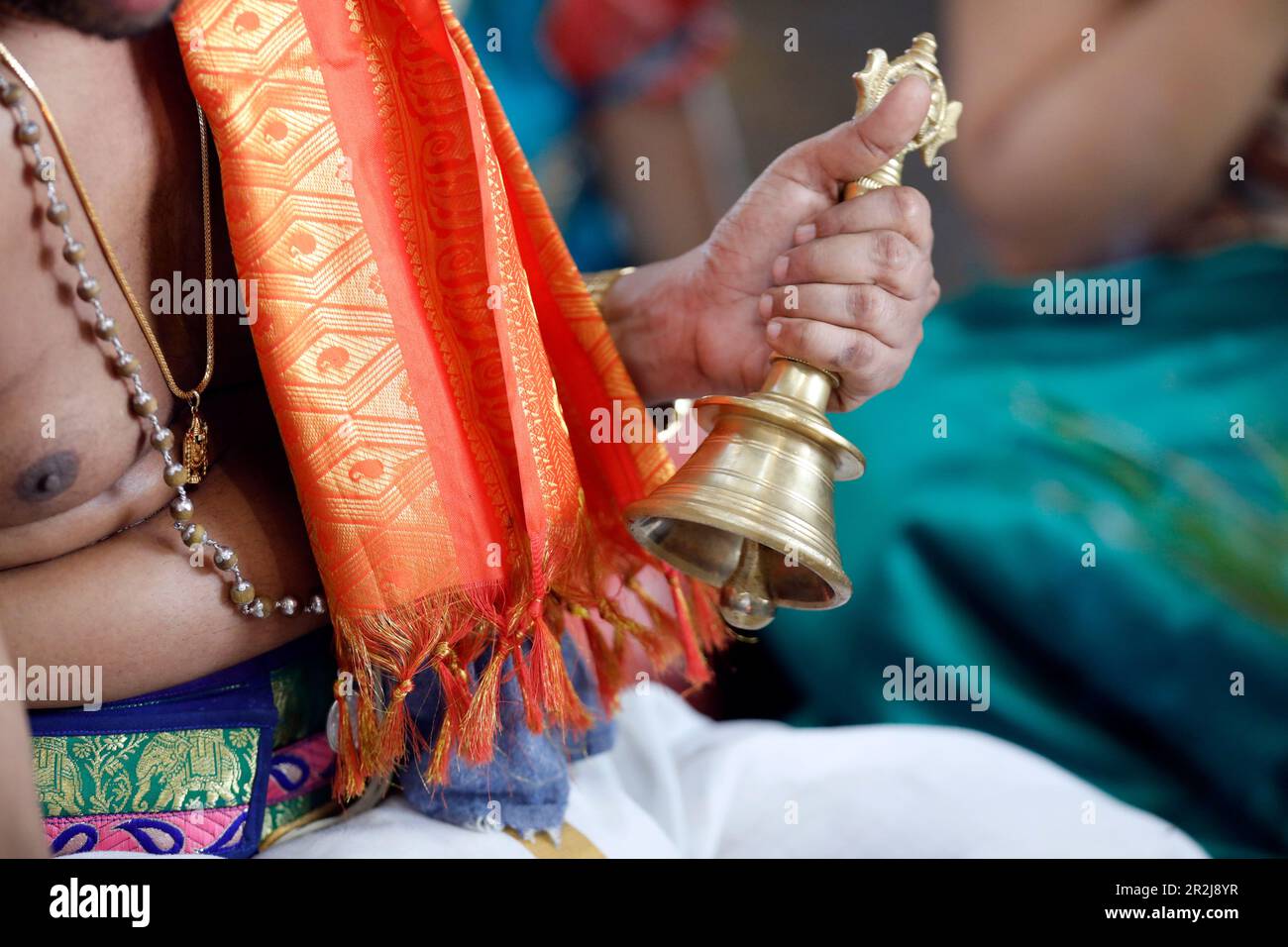 Hand holding ceremonial bell, Sri Srinivasa Perumal Hindu temple, Hindu priest (Brahmin) performing puja ceremony and rituals, Singapore Stock Photo