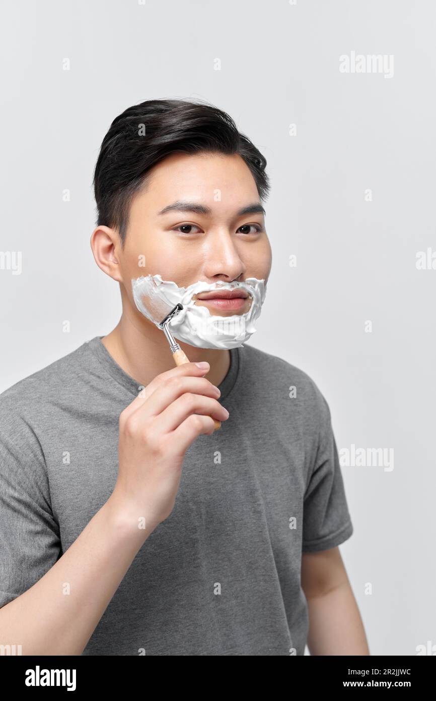 handsome man using shaving foam before shaving while standing in front