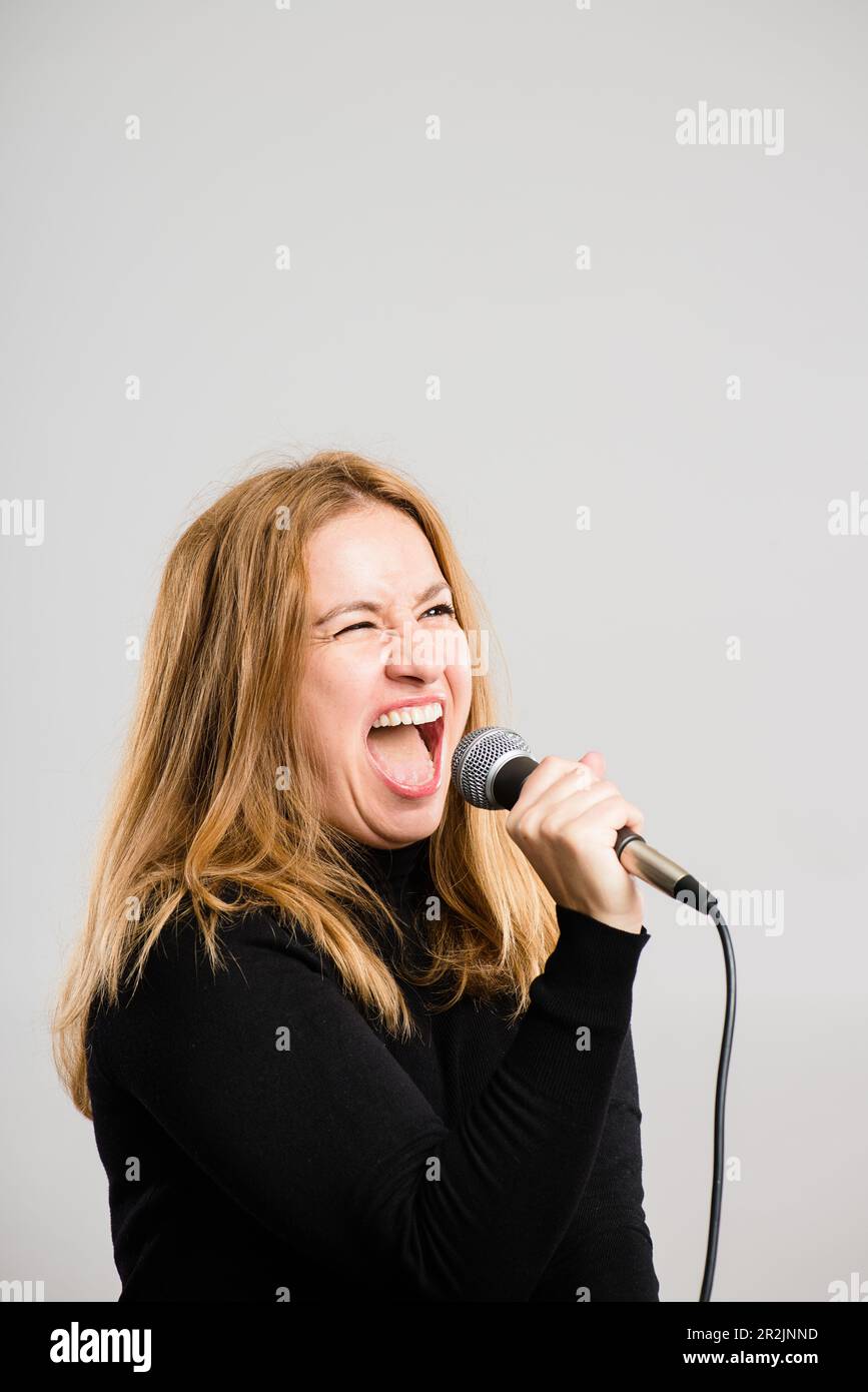 Singing my lungs out. a mature woman standing alone in the studio and using a microphone to sing karaoke. Stock Photo