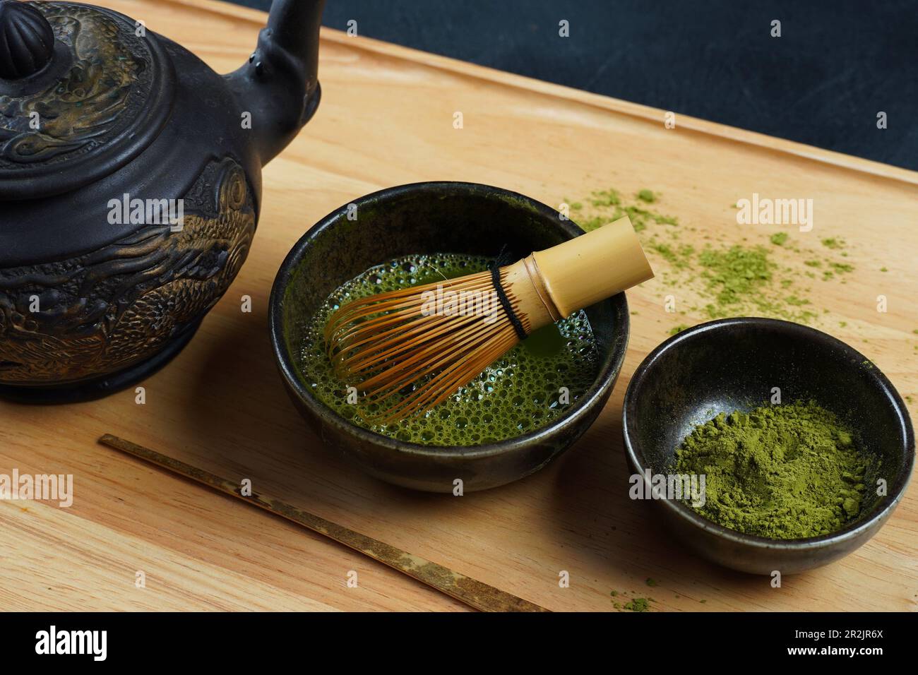 Green matcha tea powder with a bamboo whisk and scoop as used in a