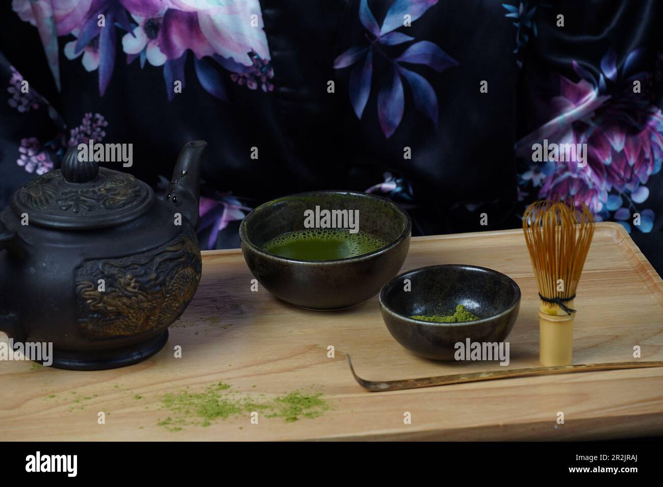 Green matcha tea powder with a bamboo whisk and scoop as used in a