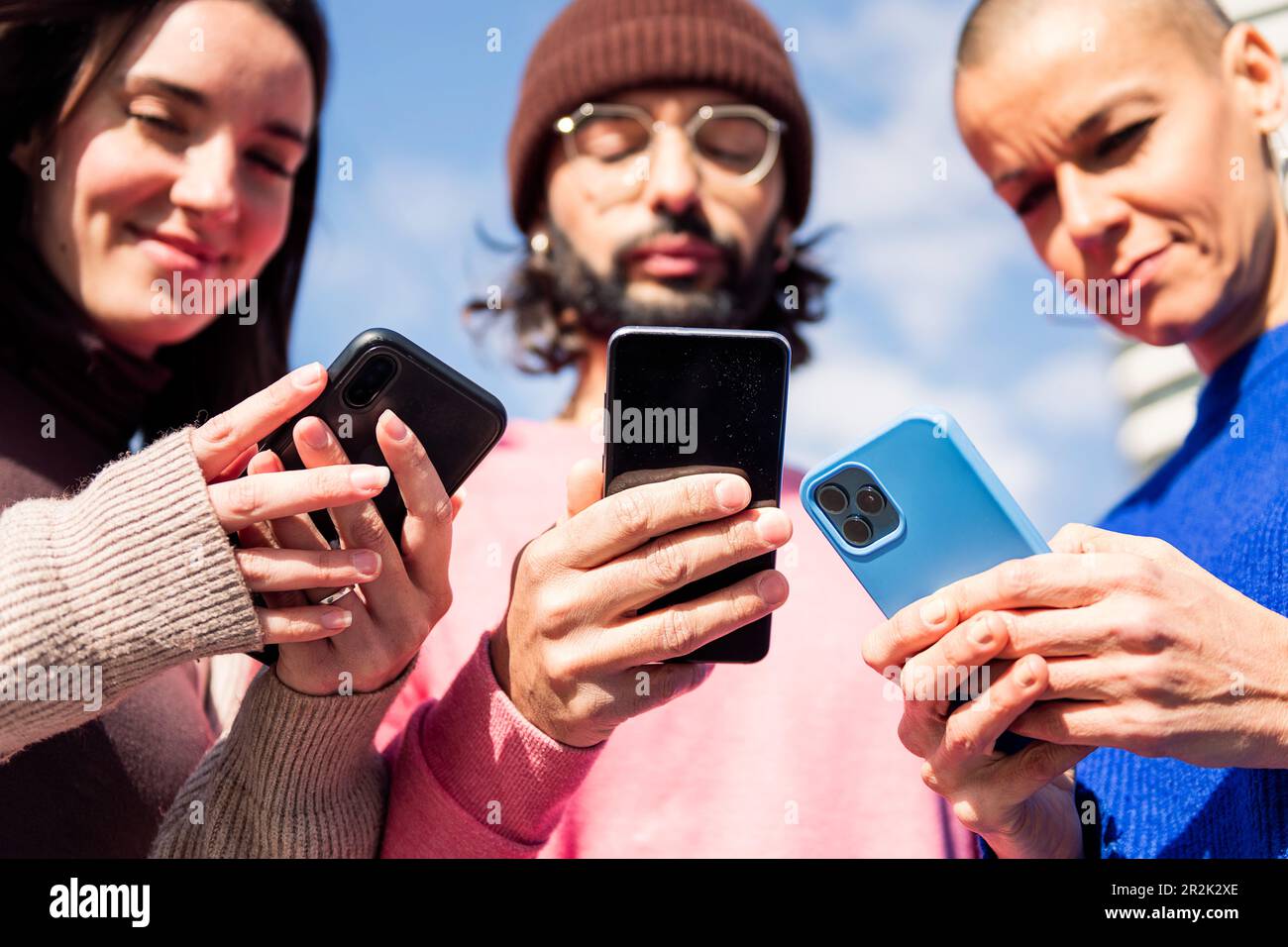 three young friends using mobile phones Stock Photo