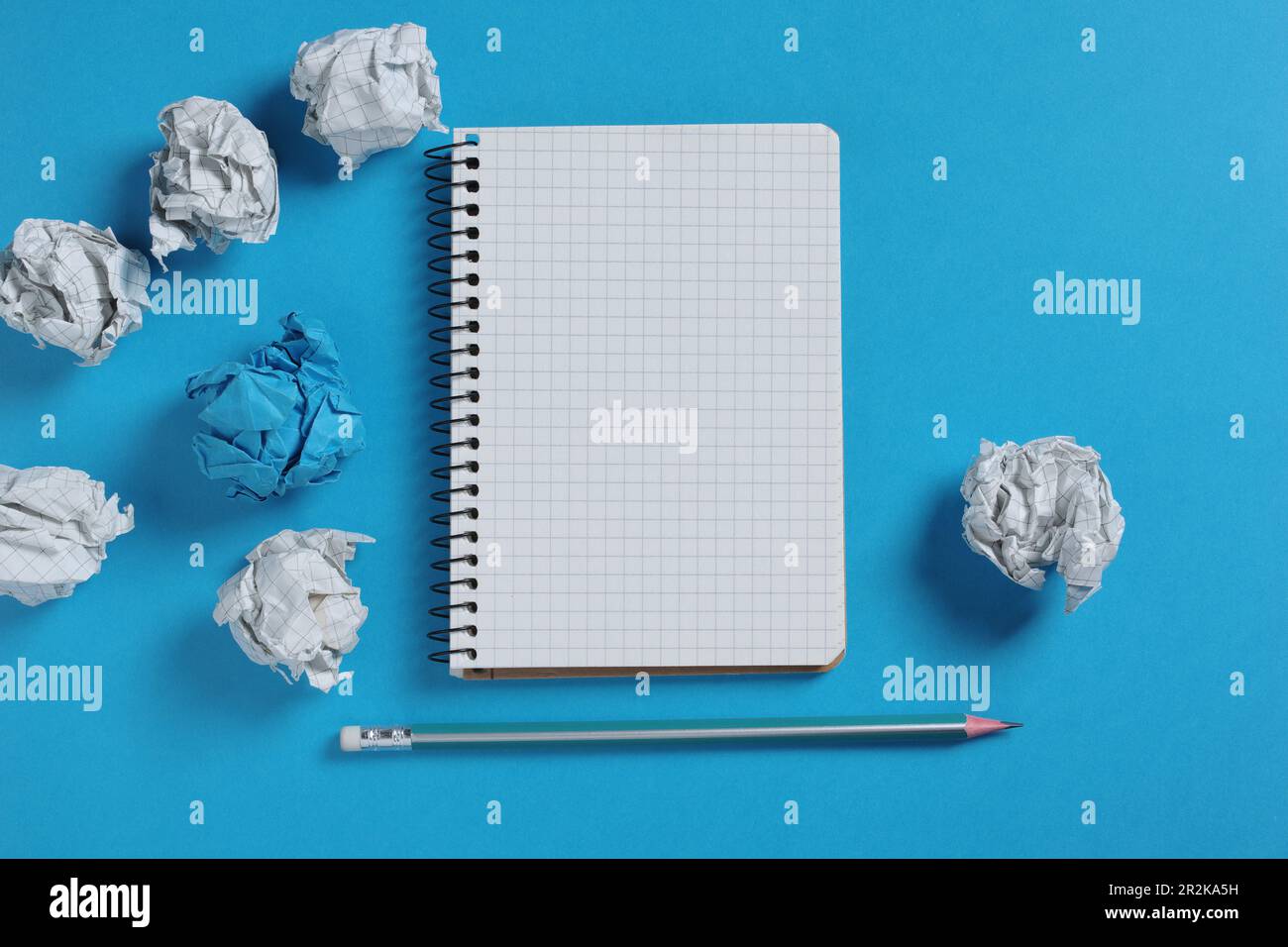 Notebook and paper balls on blue background, top view Stock Photo