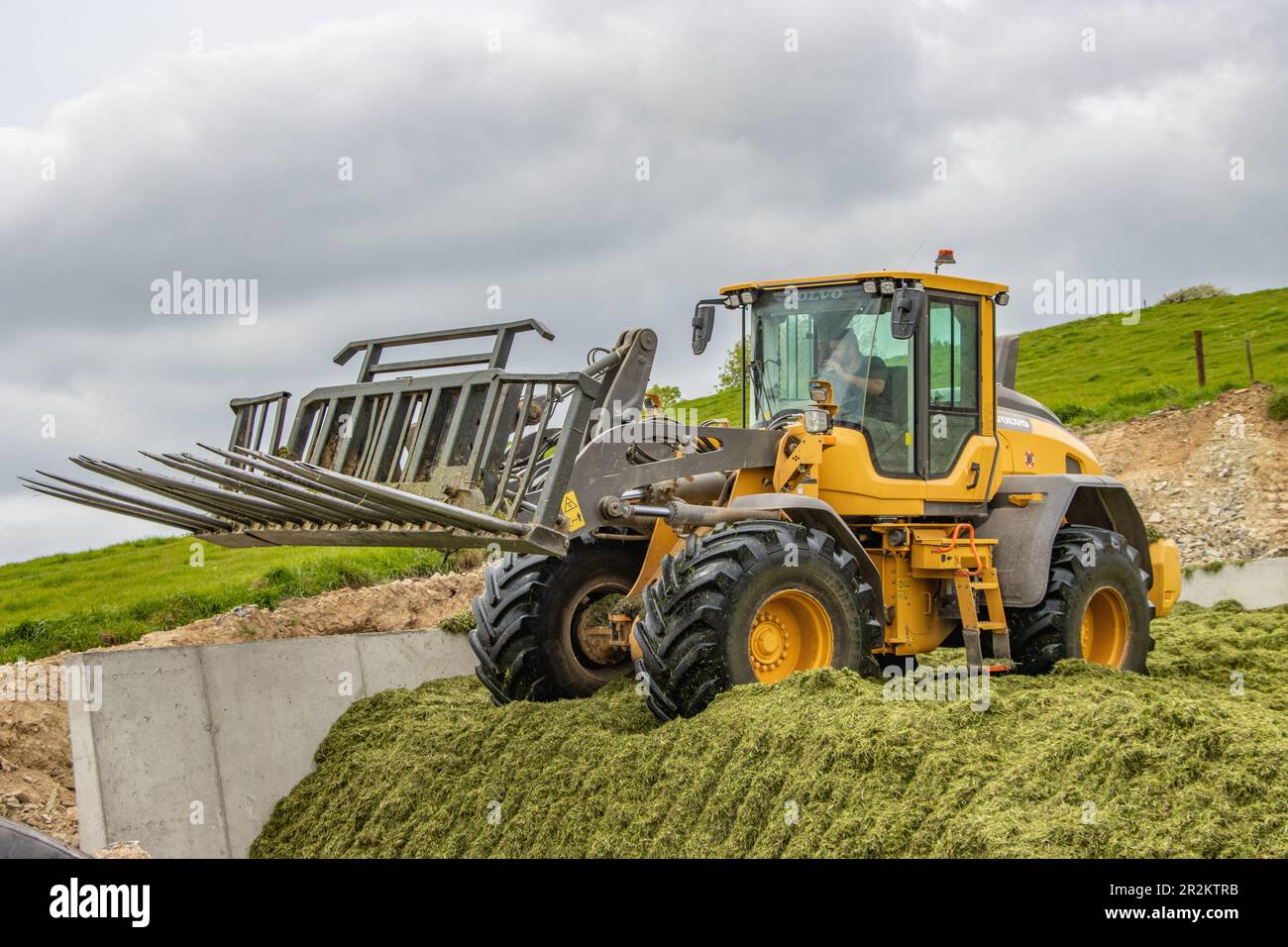 Volvo L90H loader packing grass silage pit near Timolegue, Co. Cork Stock Photo