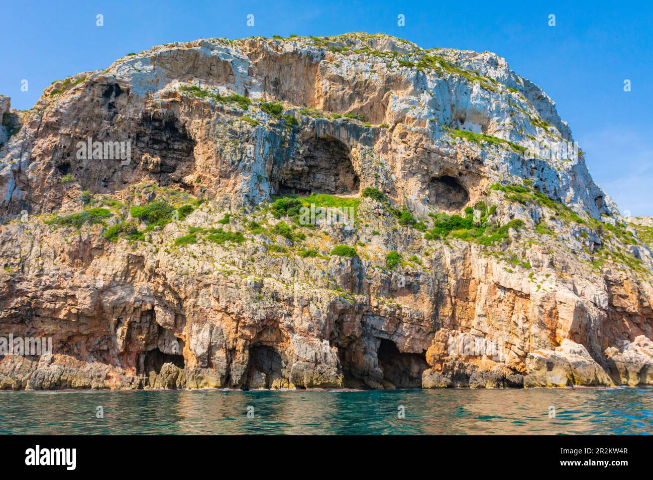 Cliffs with caves on the rocky coast of the Montgo natural park, in Denia and Javea, in Alicante, Spain Stock Photo