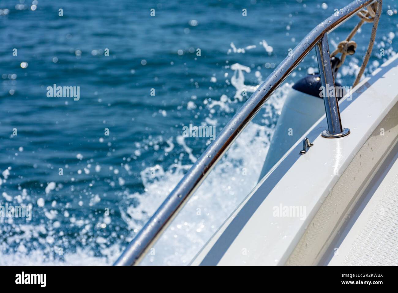 Port edge of a small recreational boat sailing in the sea, with outboard protection and water splashing Stock Photo