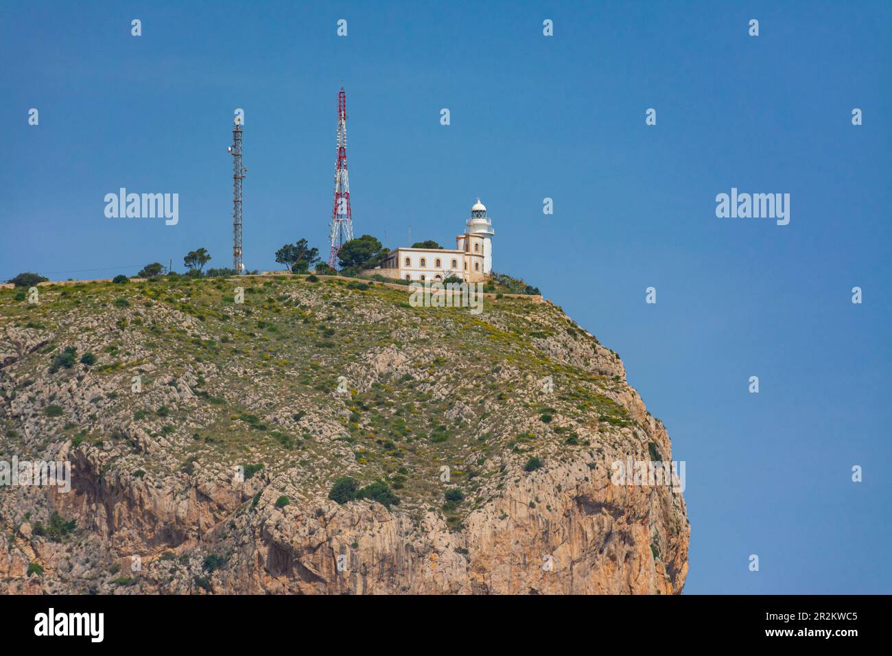 Lighthouse of Cabo de San Antonio, in Jávea, in the Montgo natural park. Small lighthouse on top of the cliff. From the sea aboard a boat Stock Photo