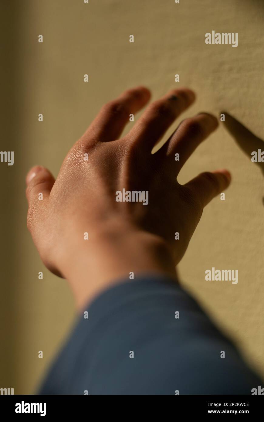 View of a hand of a girl touches a wall in sunlight Stock Photo