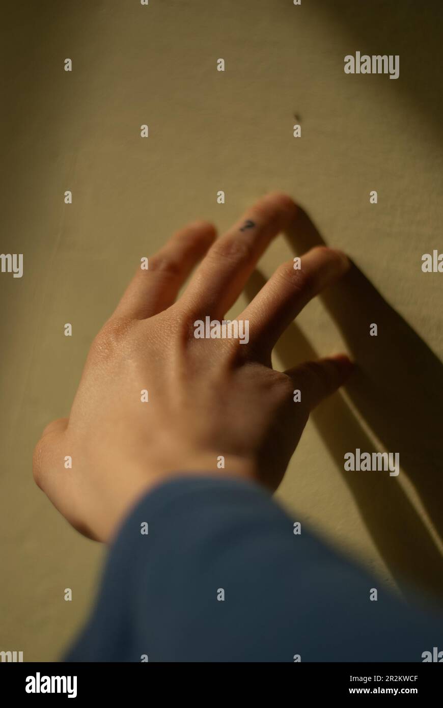 View of a hand of a girl touches a wall in morning sunlight Stock Photo