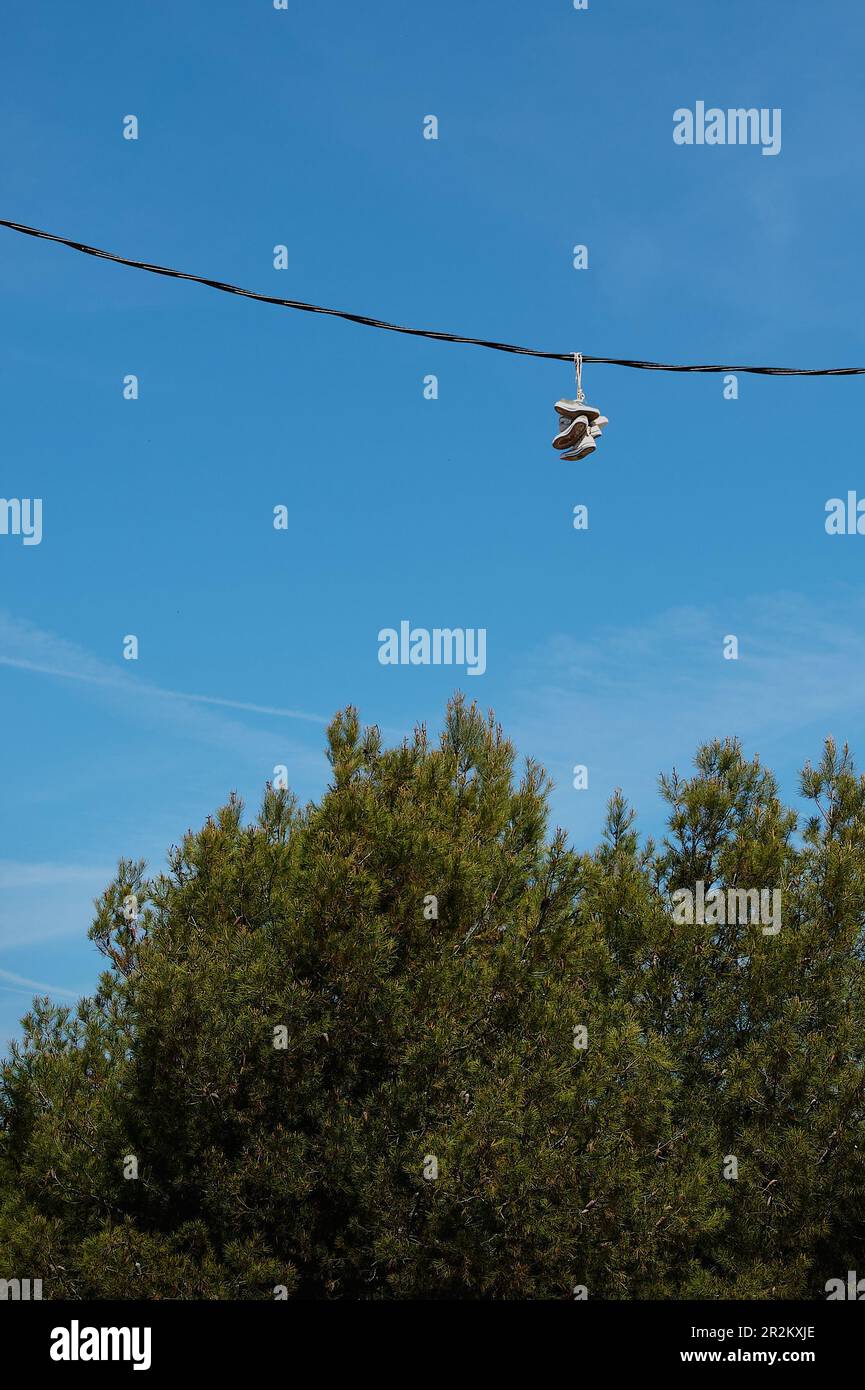 Sneakers hanging on the power lines. Shoe tossing. Fun or marking territory. Stock Photo