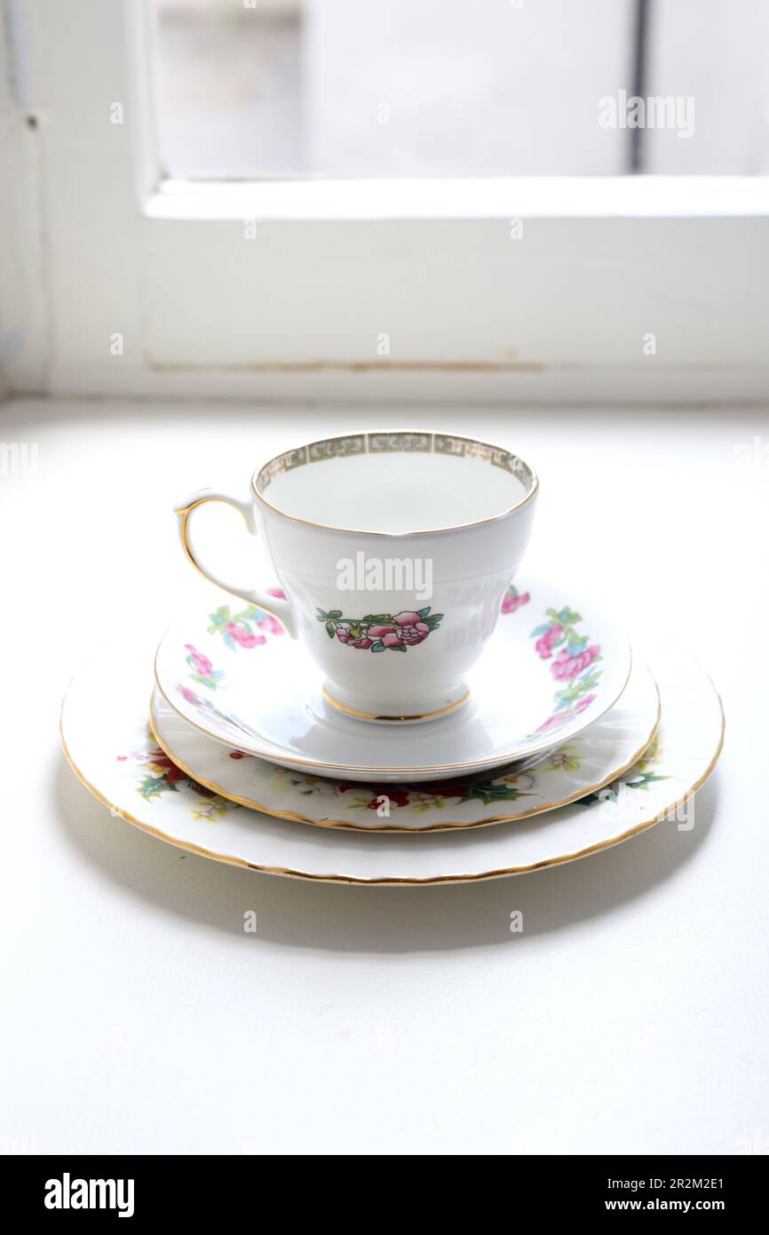 An old teacup and saucer in a brightly lit window sill. Stock Photo