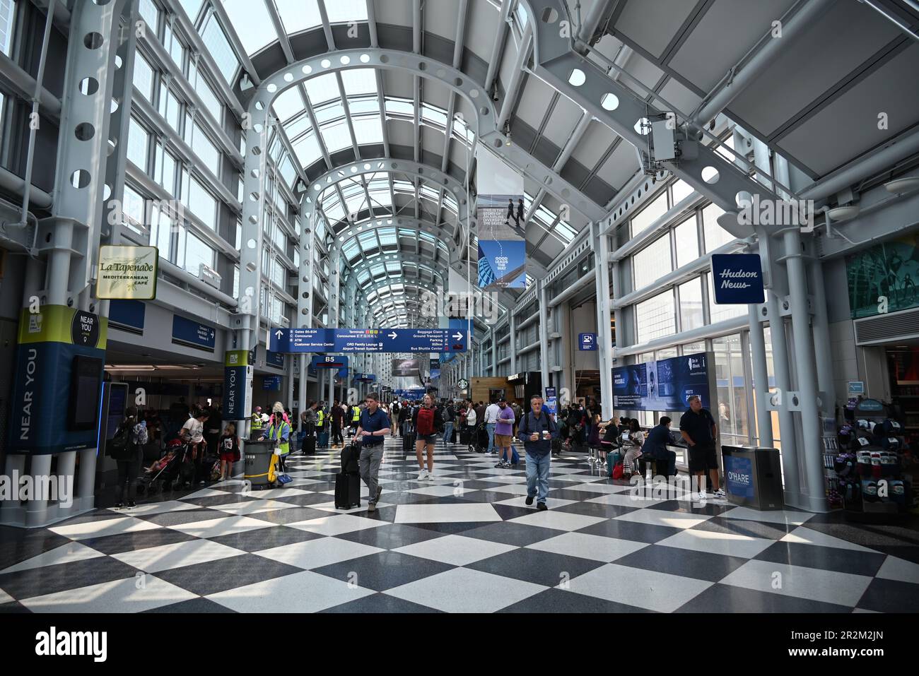 Travelers walk the long hallway between gates in Terminal One of
