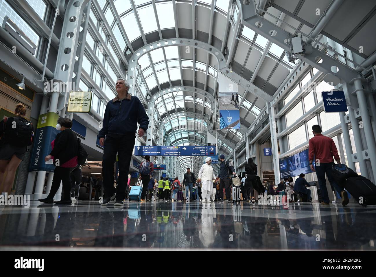 Travelers walk the long hallway between gates in Terminal One of