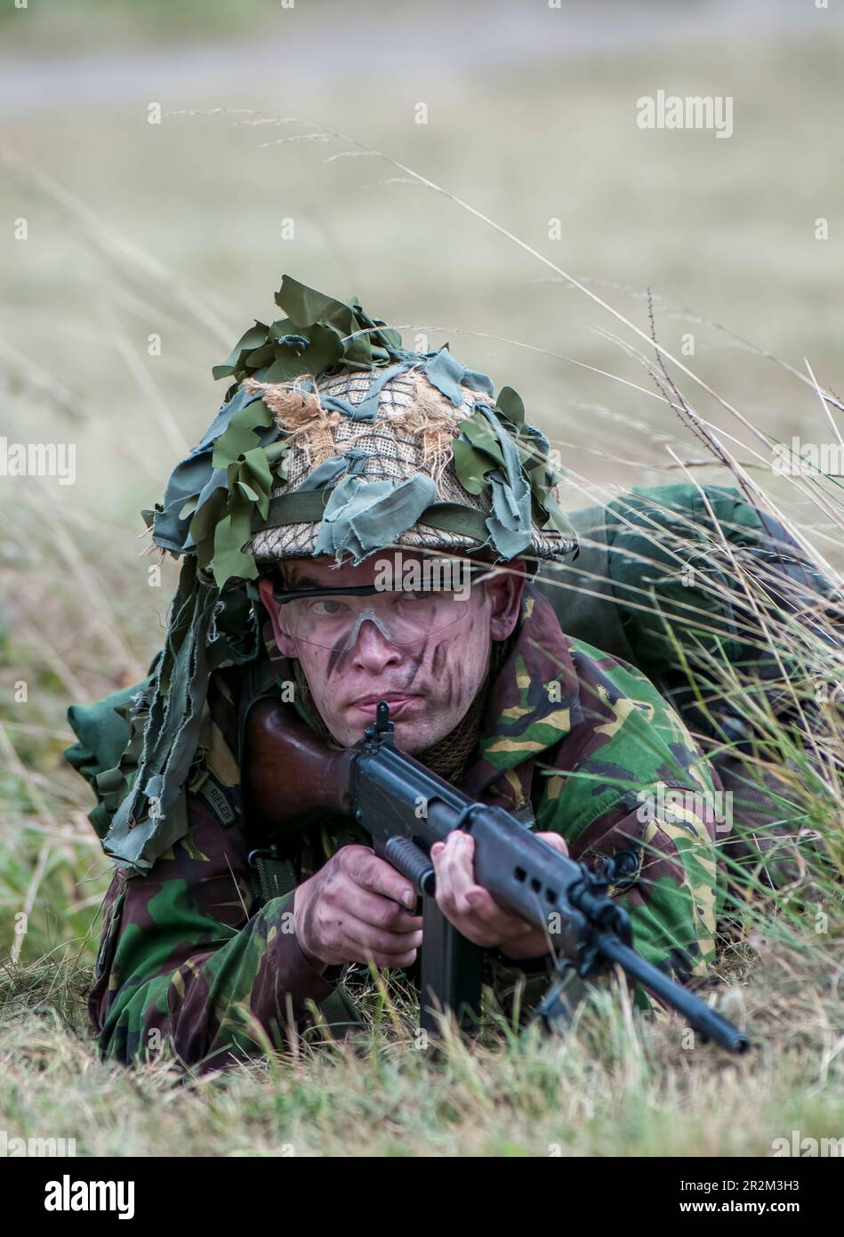 1970 British Army soldier in camouflage suit and steel helmet carrying ...