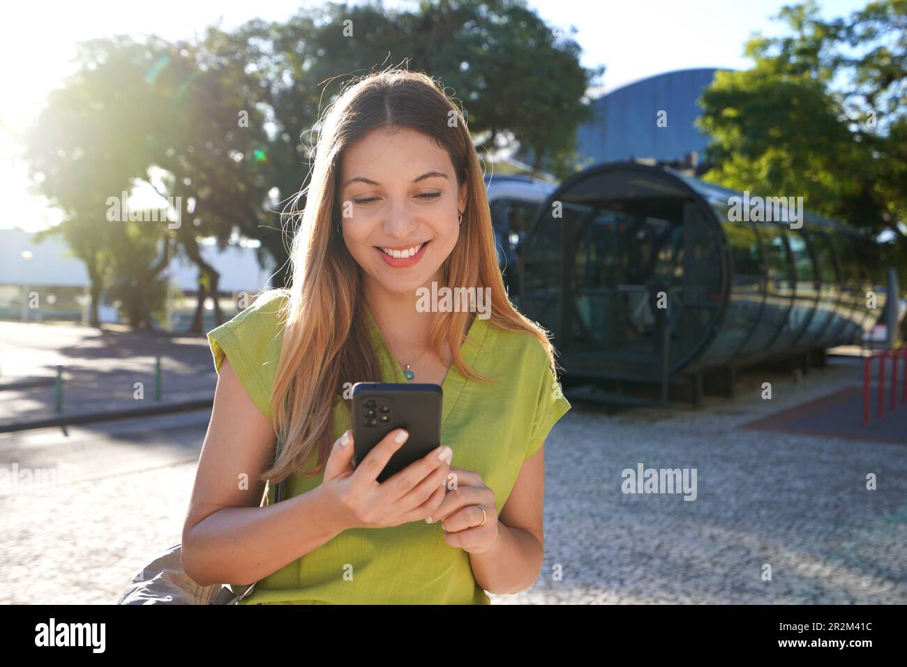 Portrait of happy smiling young woman using mobile phone in Curitiba, Brazil Stock Photo