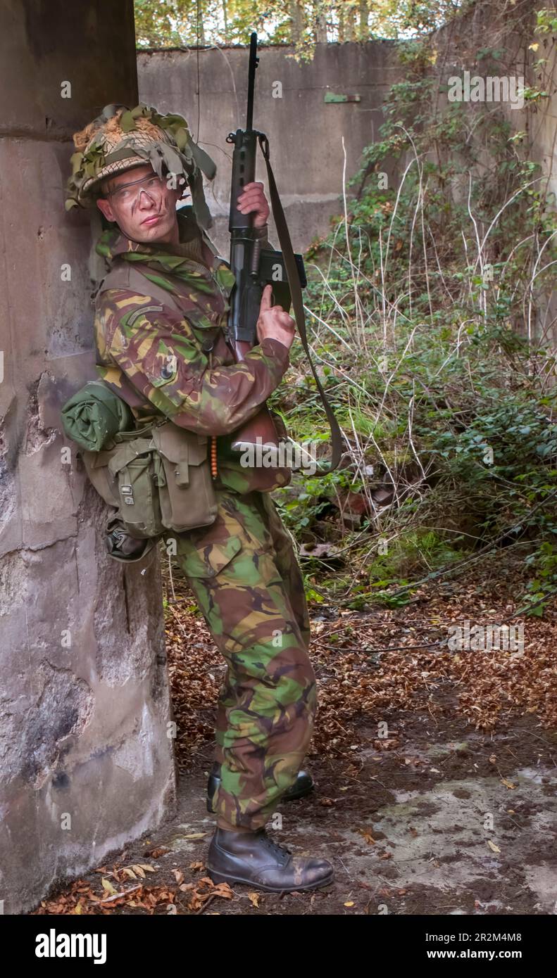 1970 British Army soldier in camouflage suit and steel helmet carrying ...