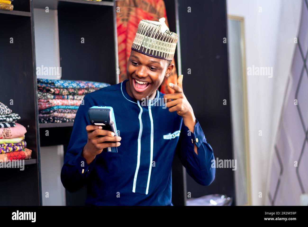 african man wearing african attire selling in a fashion market using a