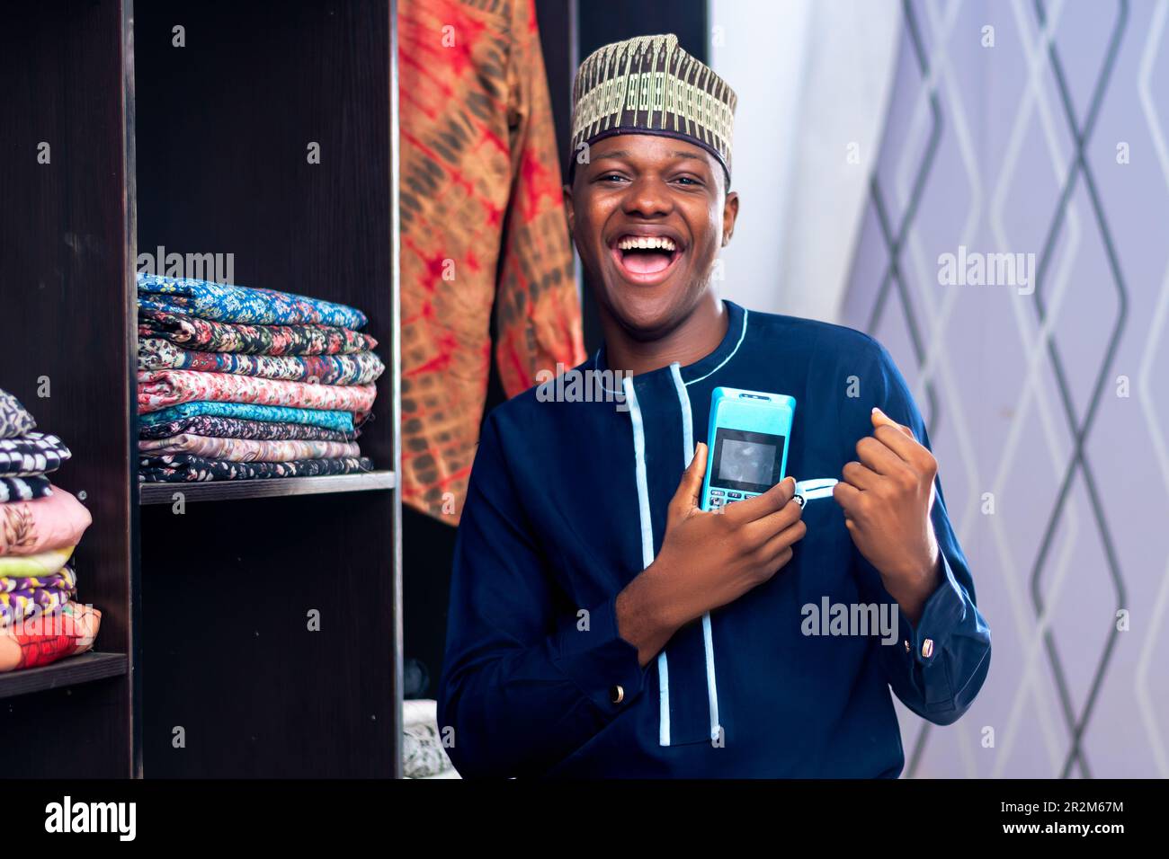 african man wearing african attire selling in a fashion market using a