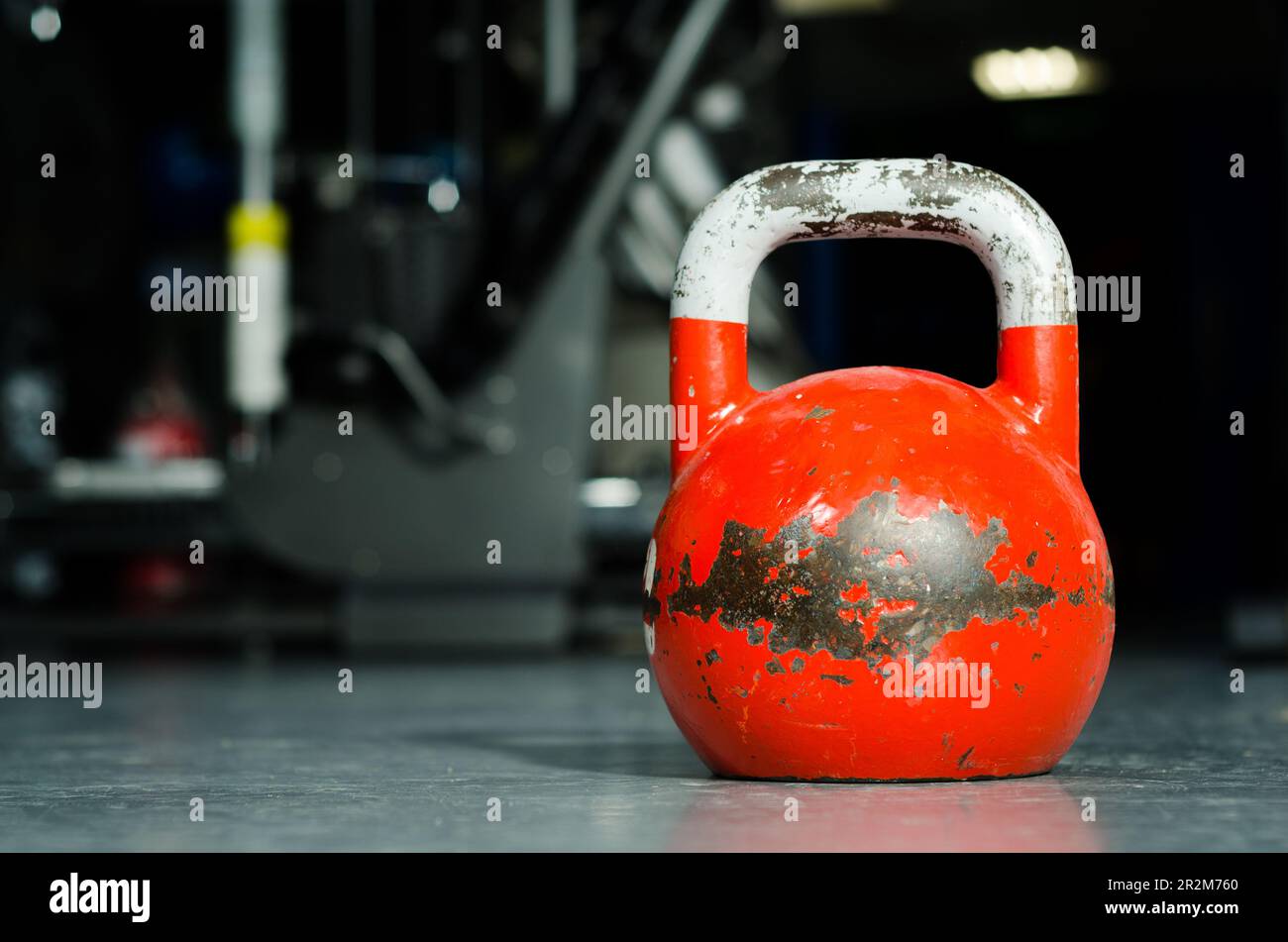 Old used red kettlebell on the gym floor ready for crossfit strength