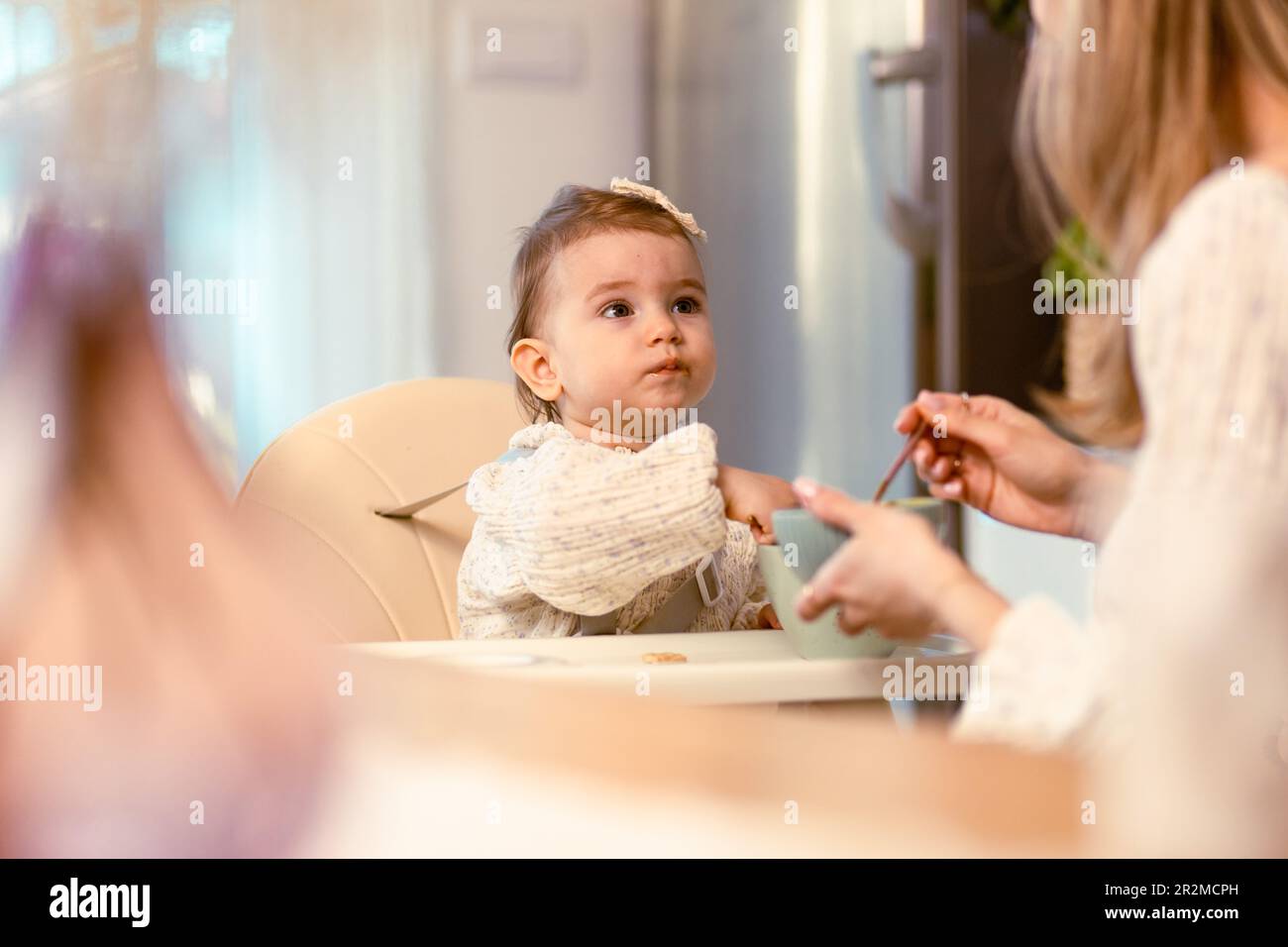 Young mom feeding her baby daughter with a spoon Stock Photo