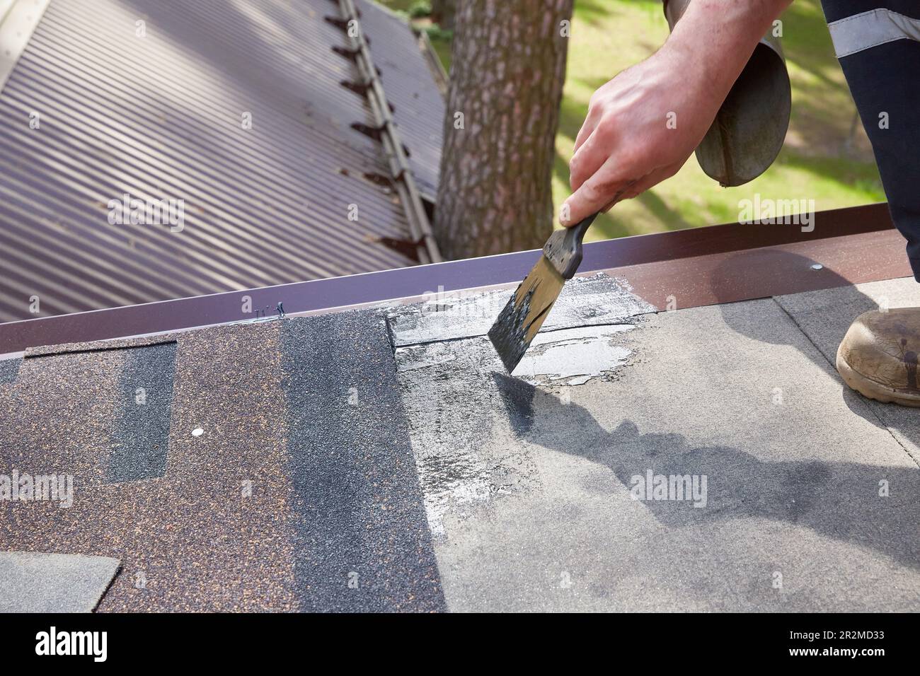 Repair and construction. The hands of the worker apply mastic on the roof of the house Stock