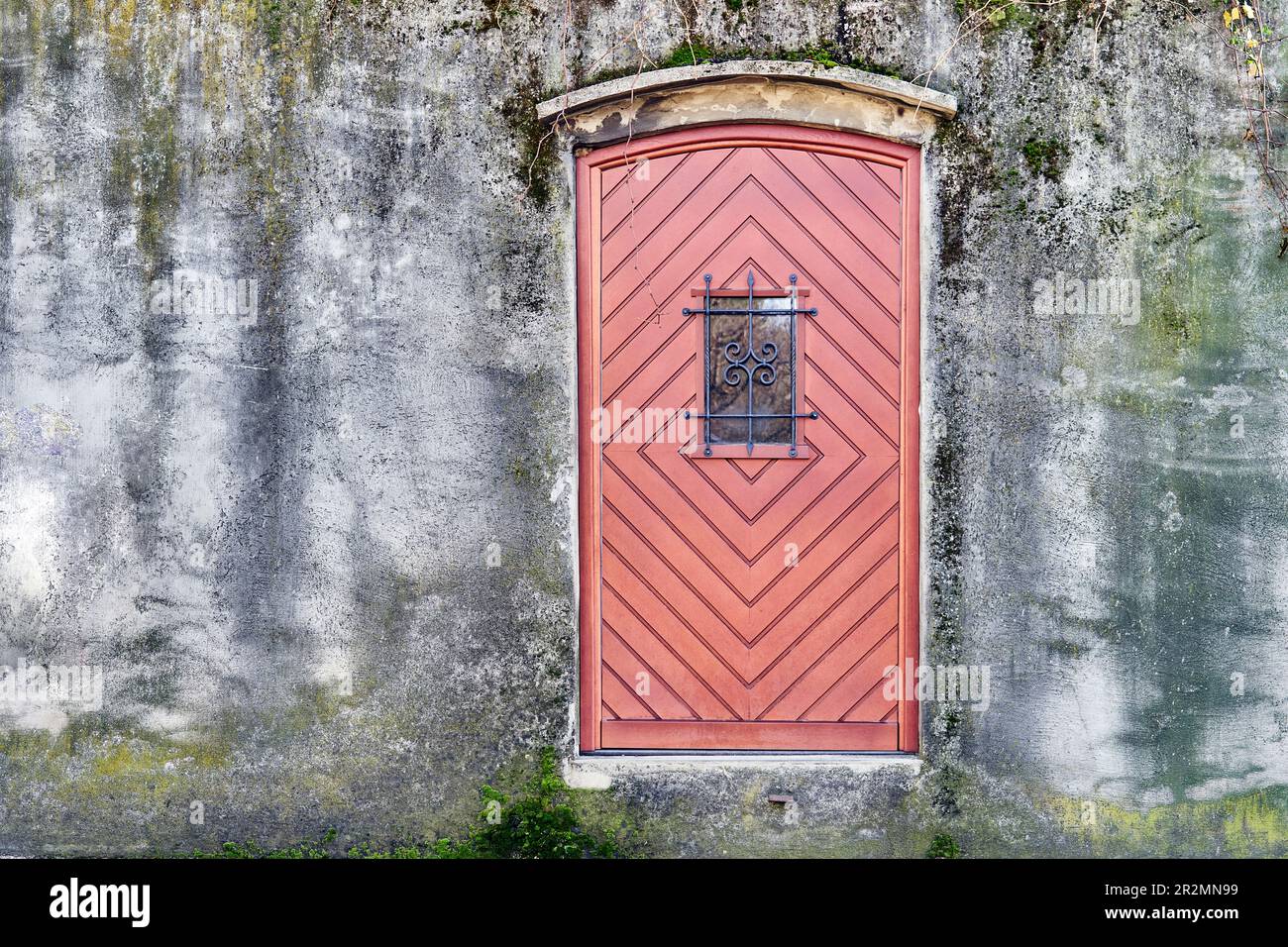 Red wooden door in weathered old stone wall Stock Photo