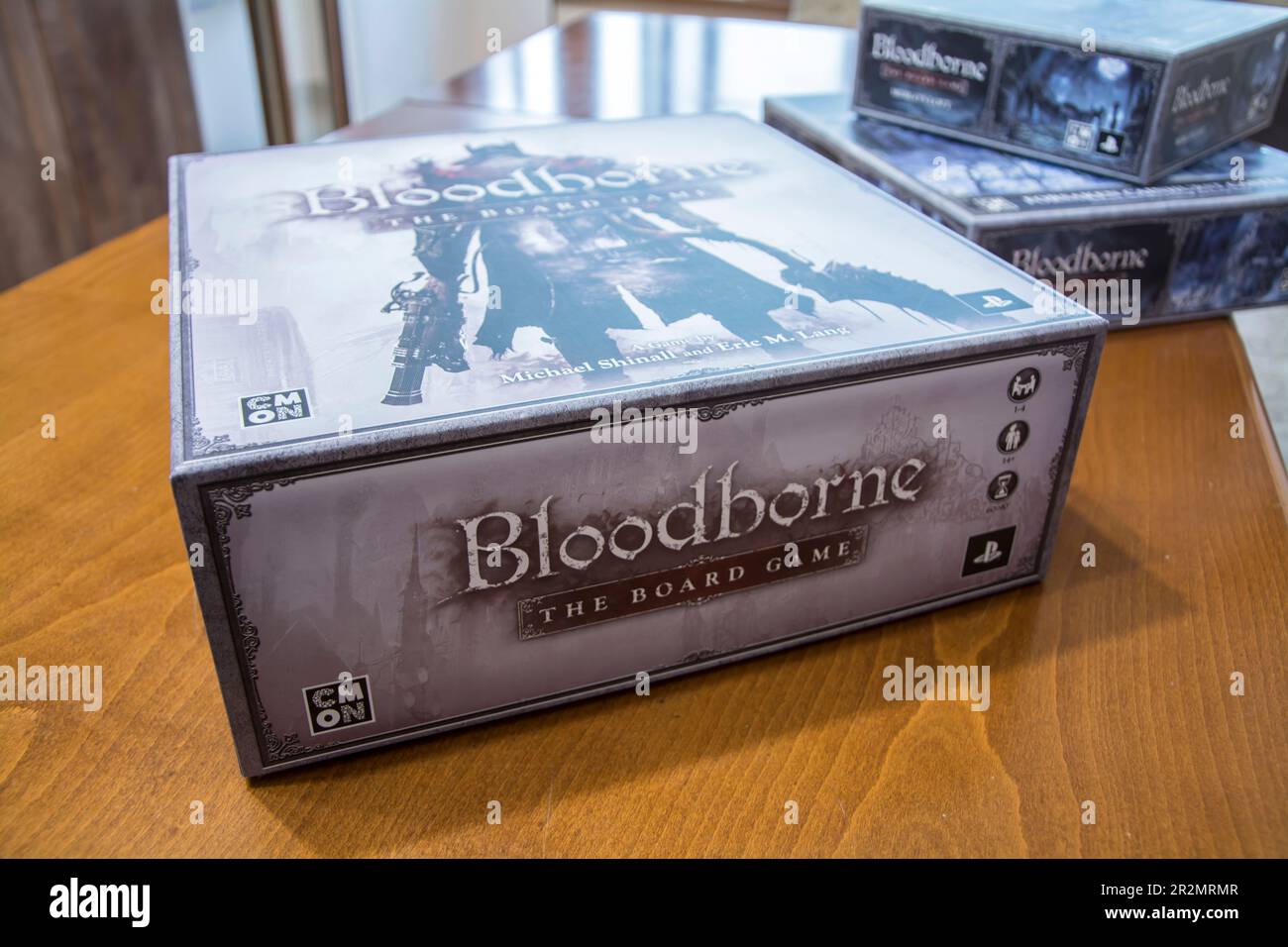 A box of the popular board game Bloodborne sitting on a table and several expansion boxes in the background. Horizontal image with selective focus Stock Photo