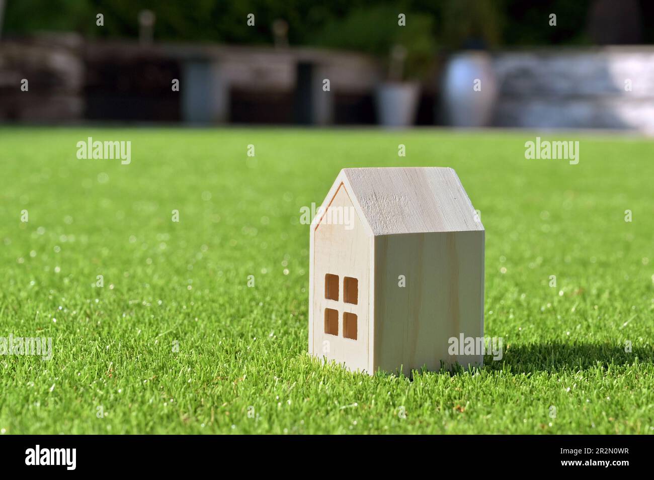 Small wooden model house on a background of short green grass. Housing concept. No people. Copy space. Stock Photo