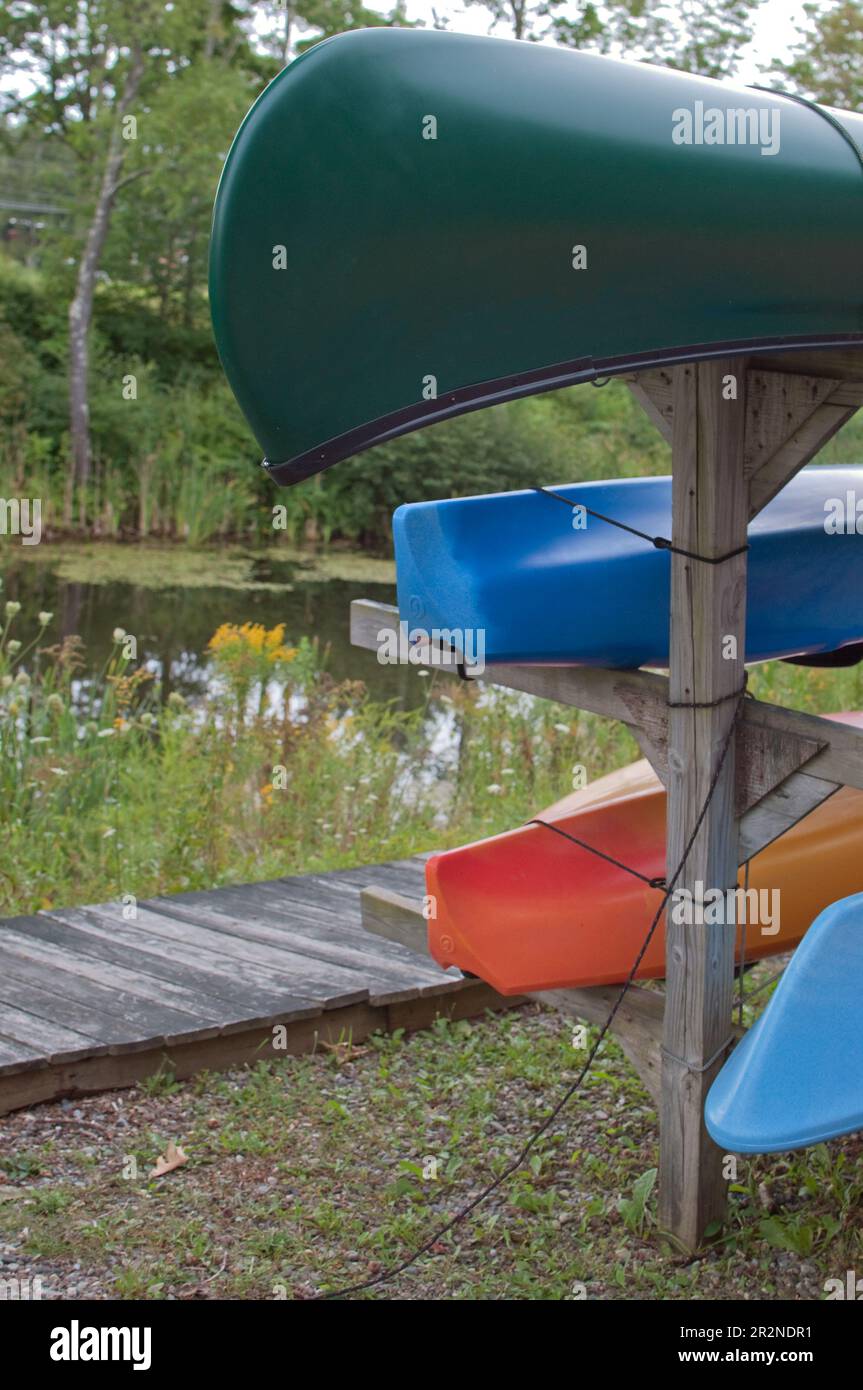 Multicolored canoes upside down on a wooden structure. No people Stock Photo Alamy