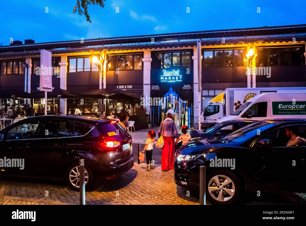 Lisbon, Portugal, People, Mum with children,  Entering into Building Local Food Market, Time Out Market, Front at Night, Street Scene with Cars Stock Photo