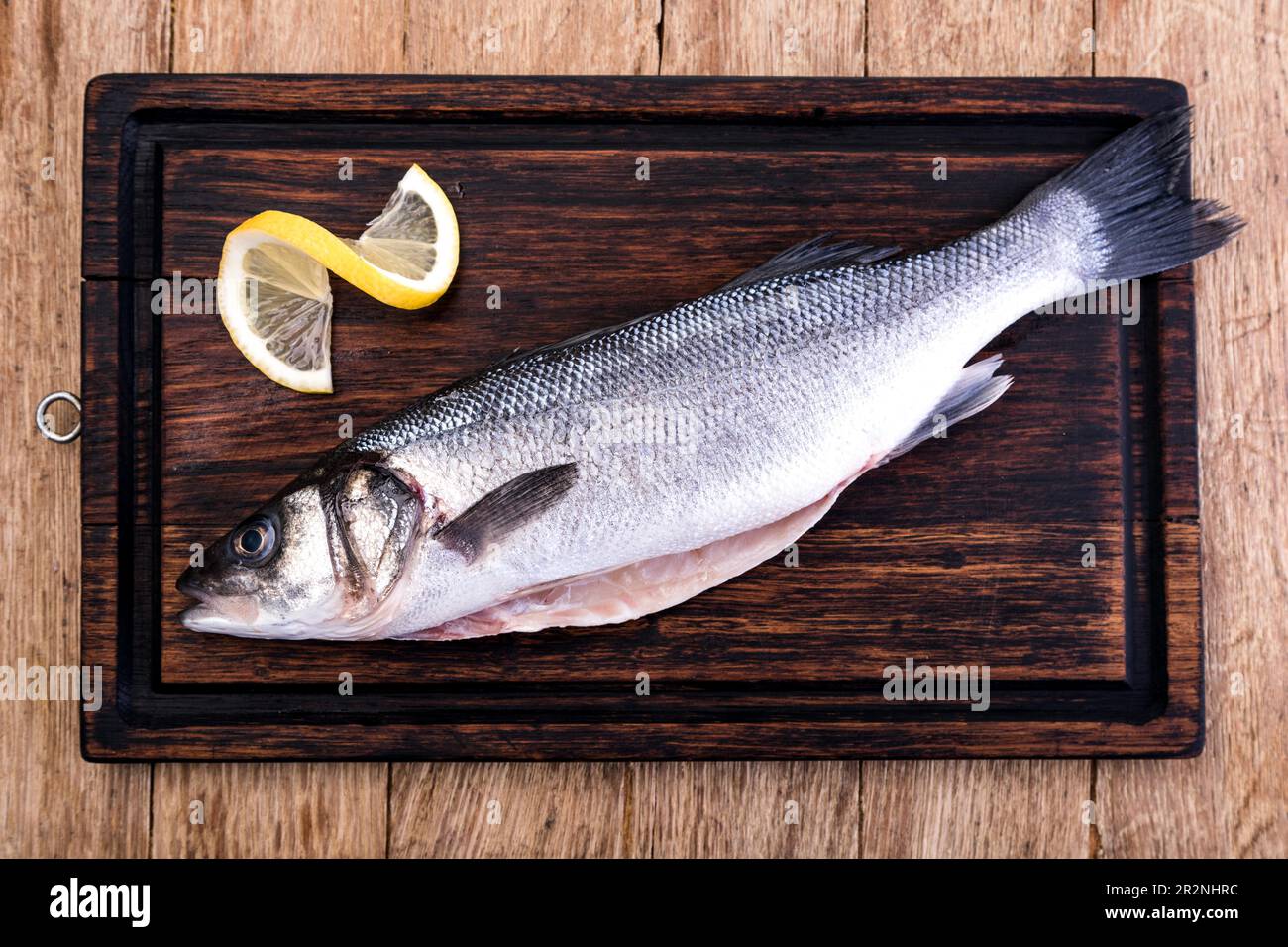 Raw Seabass isolated on a wooden table Stock Photo