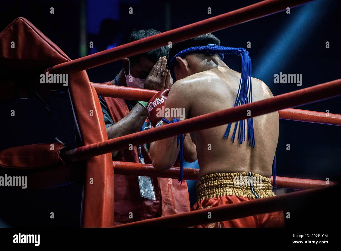 A Muay Thai boxer performs 'Wai Kru' a ritual ceremony before engaging in battle which is a thank you and blessing to show deep respect to one's coaches, training partners, and family, at Bangkok's Rajadamnern stadium. Muay Thai fights at Thailand’s iconic boxing Rajadamnern stadium, the dream stage for competitors and it is favourite for combat sports all over the world. Stock Photo