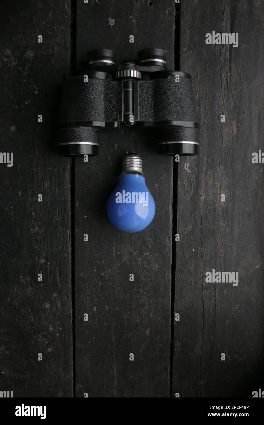 Idea concept. Blue Light lamp and vintage binoculars Stock Photo Alamy