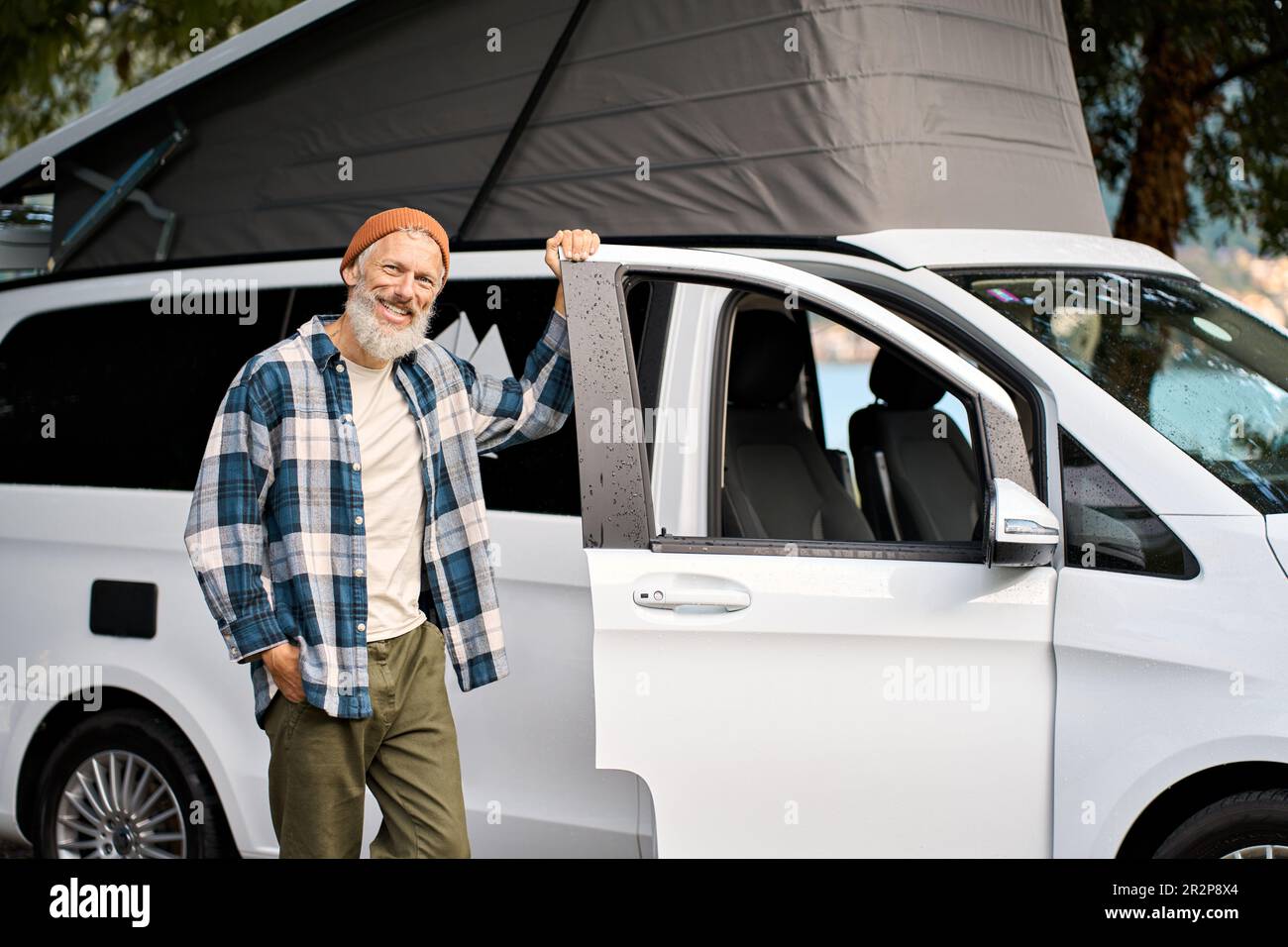 Happy older man traveler standing with camper van, campervan rentals. Stock Photo