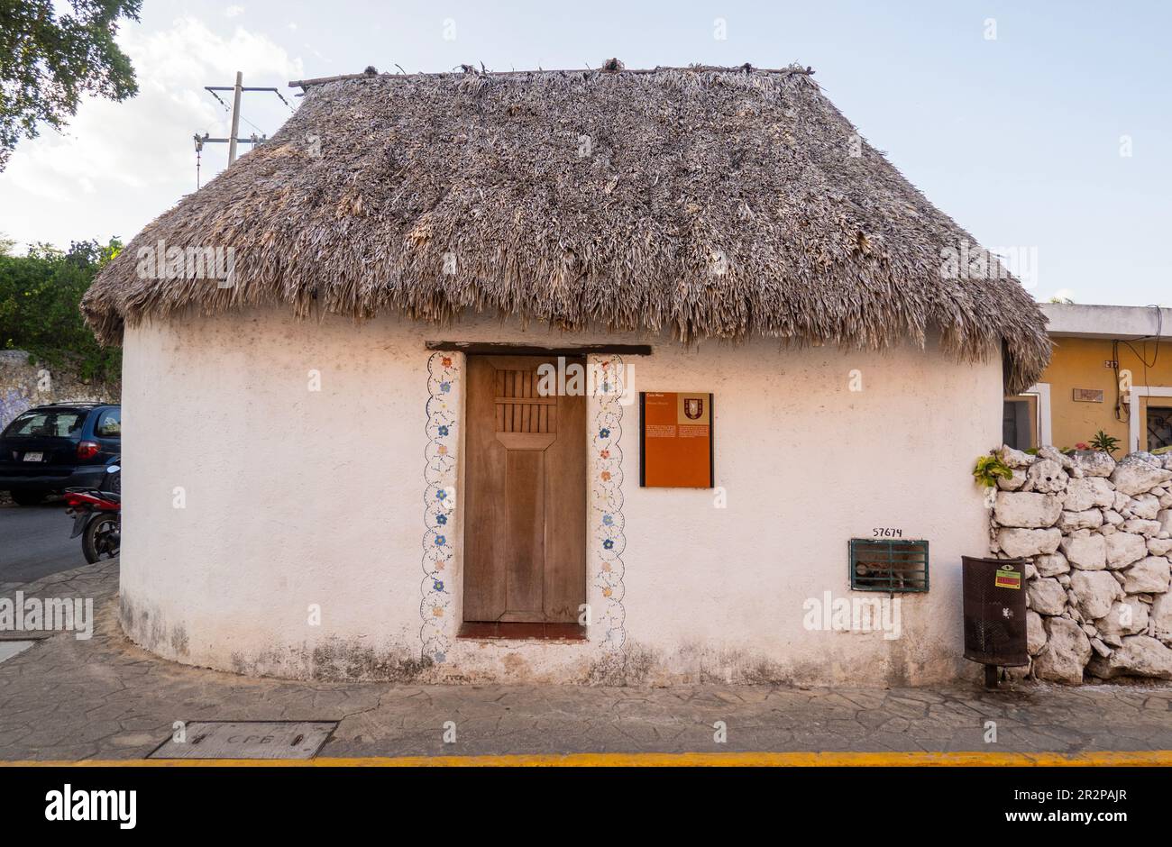 front of a small preserved and restored Mayan house made from materials