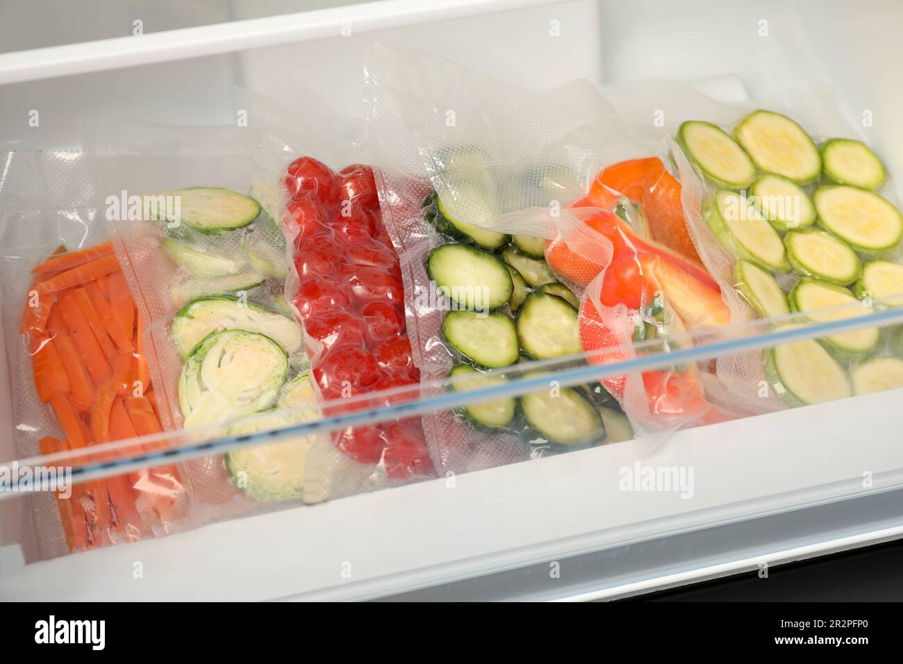 Vacuum bags with different vegetables in fridge. Food storage Stock Photo