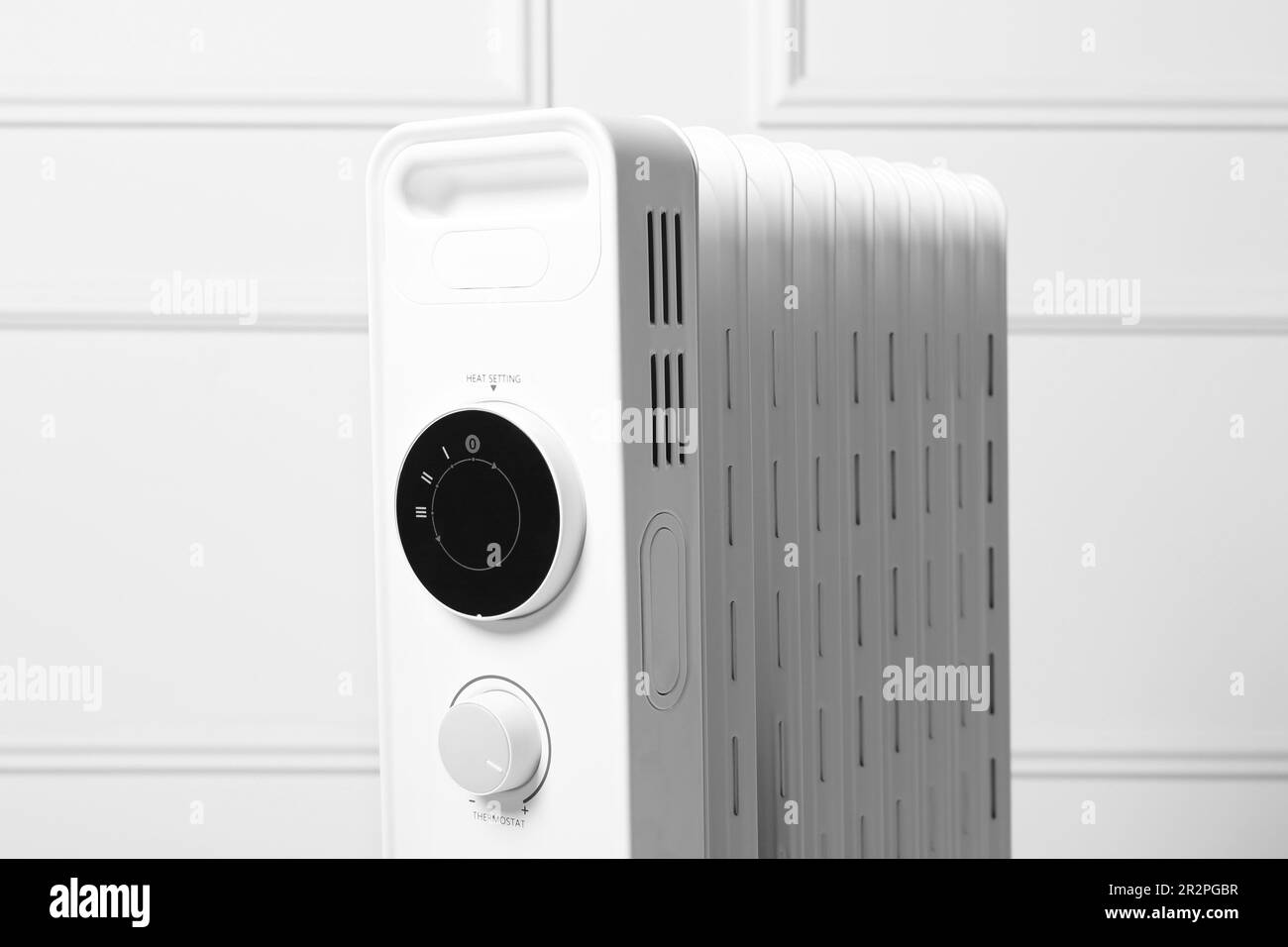 Modern portable electric heater near white wall, closeup Stock Photo
