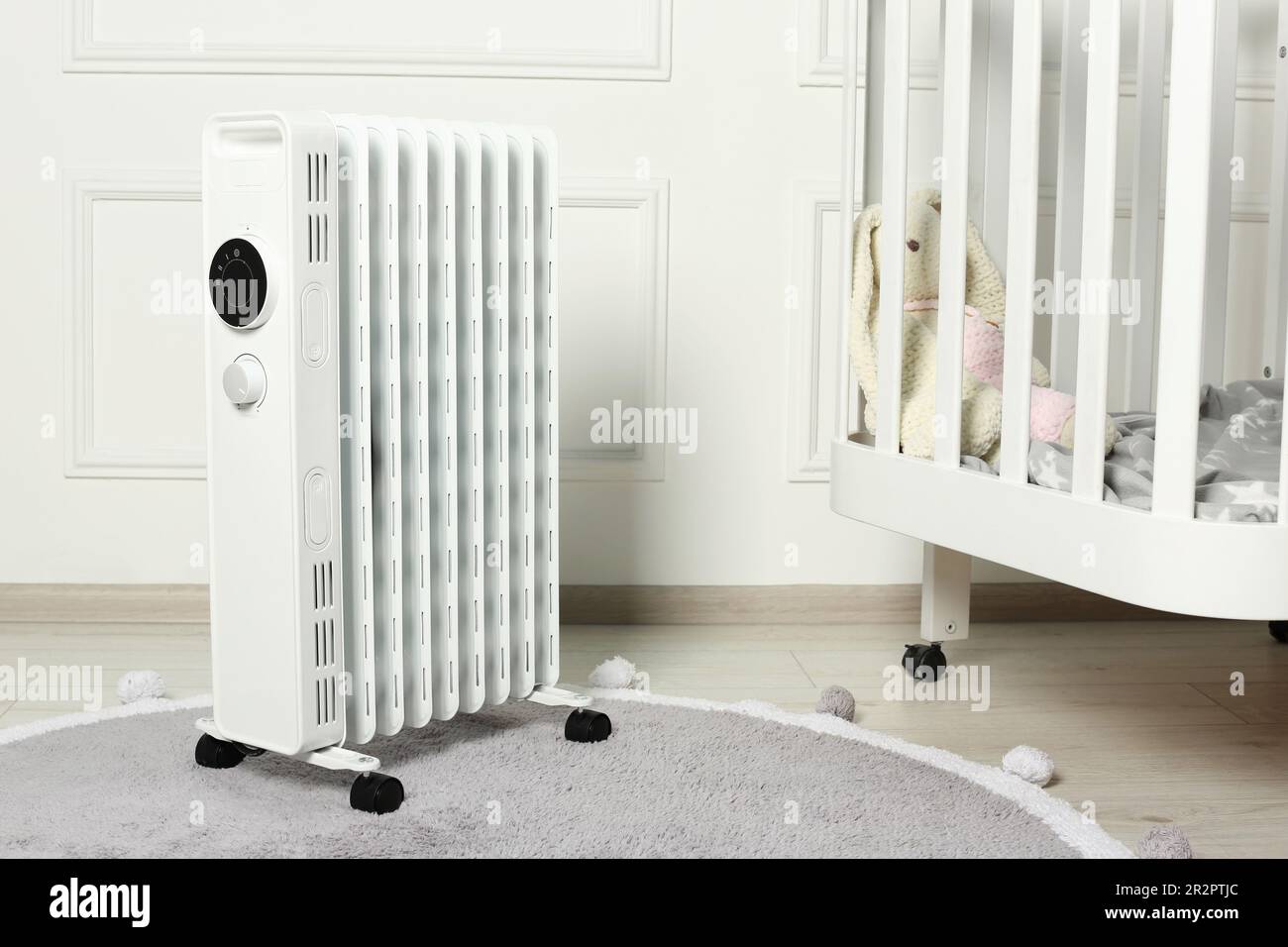 Modern portable electric heater and baby crib indoors Stock Photo Alamy
