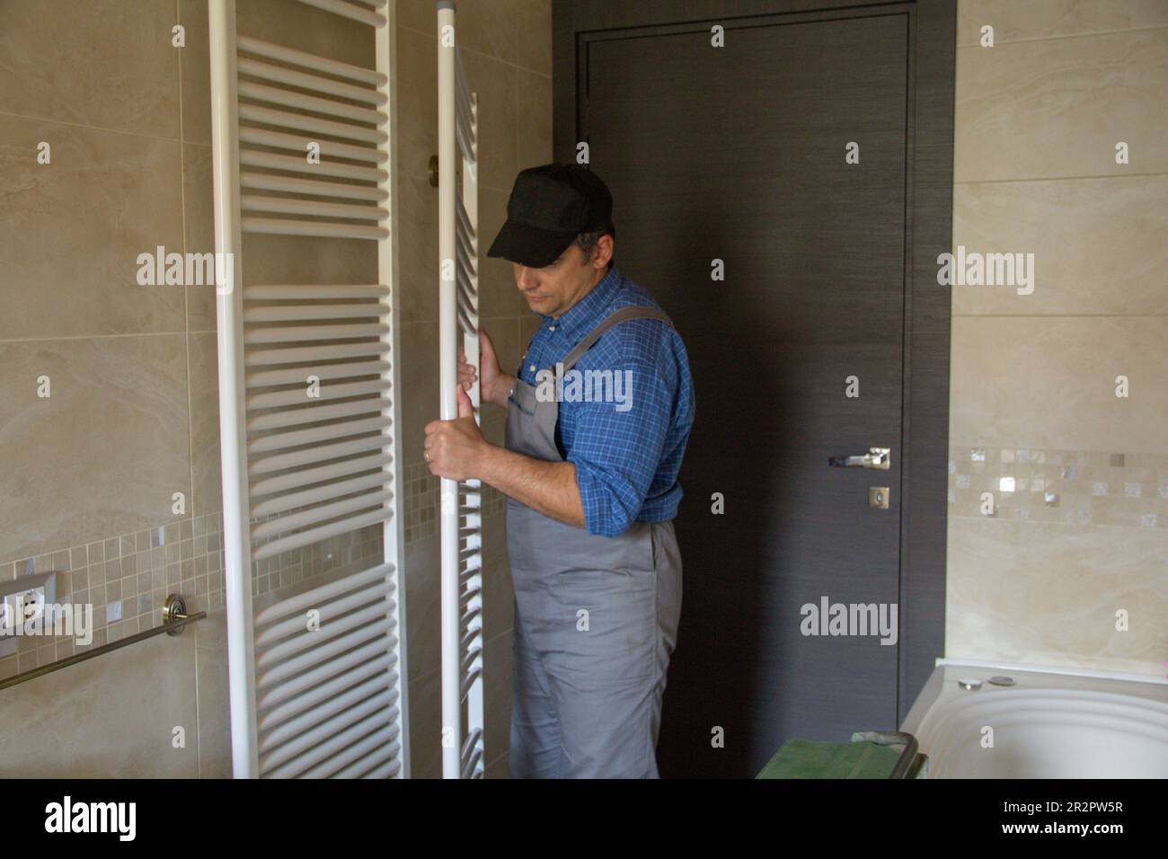 Image of a plumber while he is assembling a radiator like a towel warmer in a bathroom at home. Stock Photo