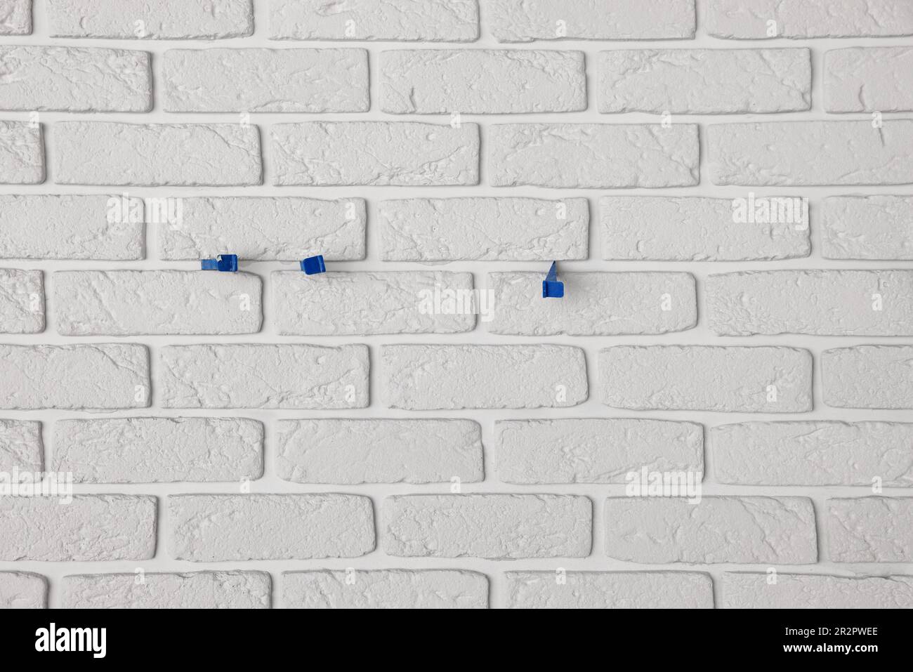 Decorative white bricks with tile leveling system on wall Stock Photo