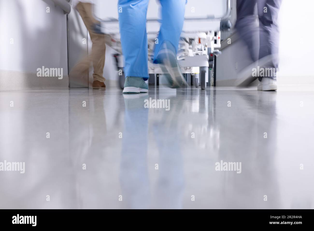 Low section of diverse doctors pushing patient in hospital bed down